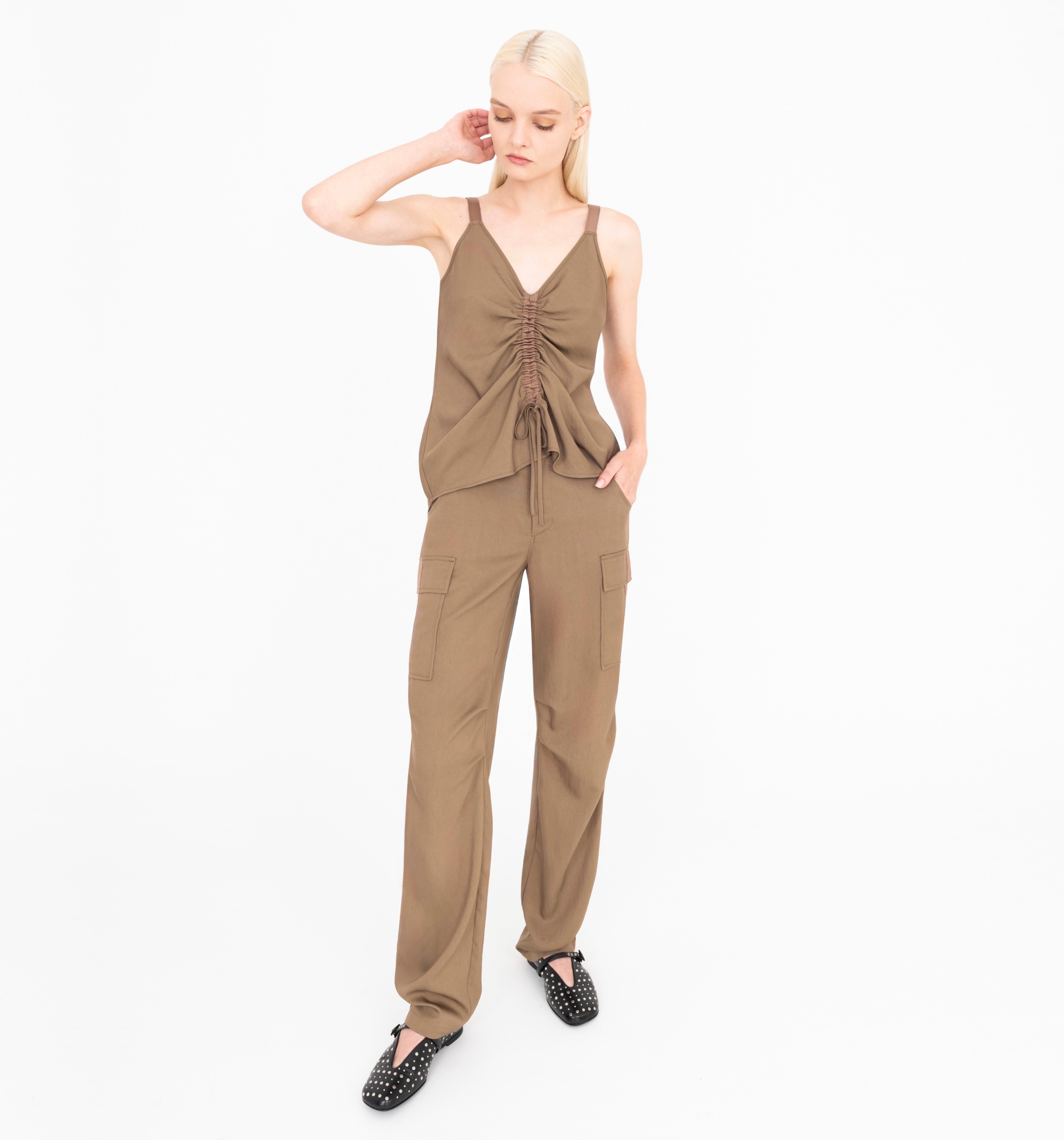 Woman wearing a brown sleeveless top and pants on a white background