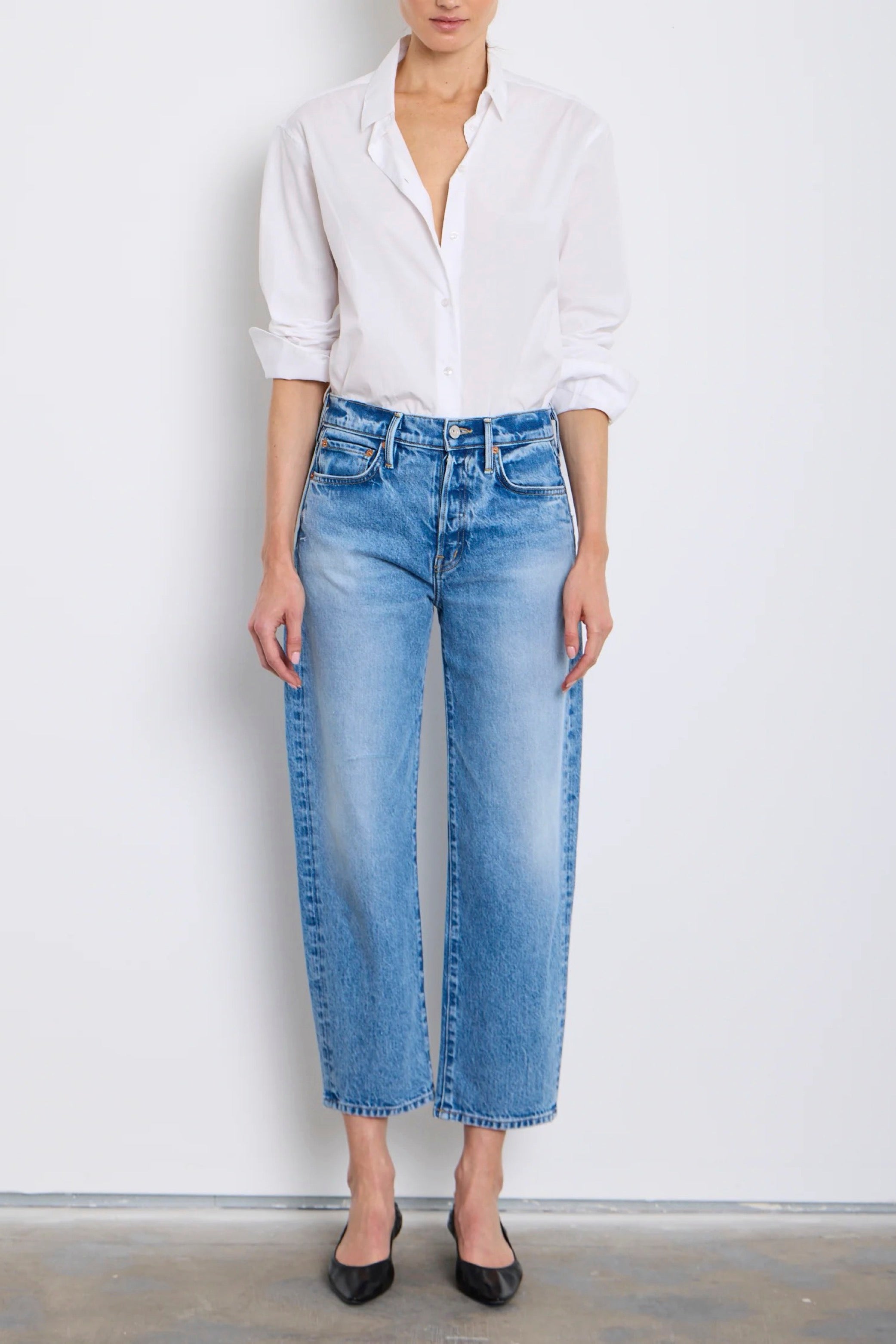 Person wearing a white shirt and blue jeans against a plain background