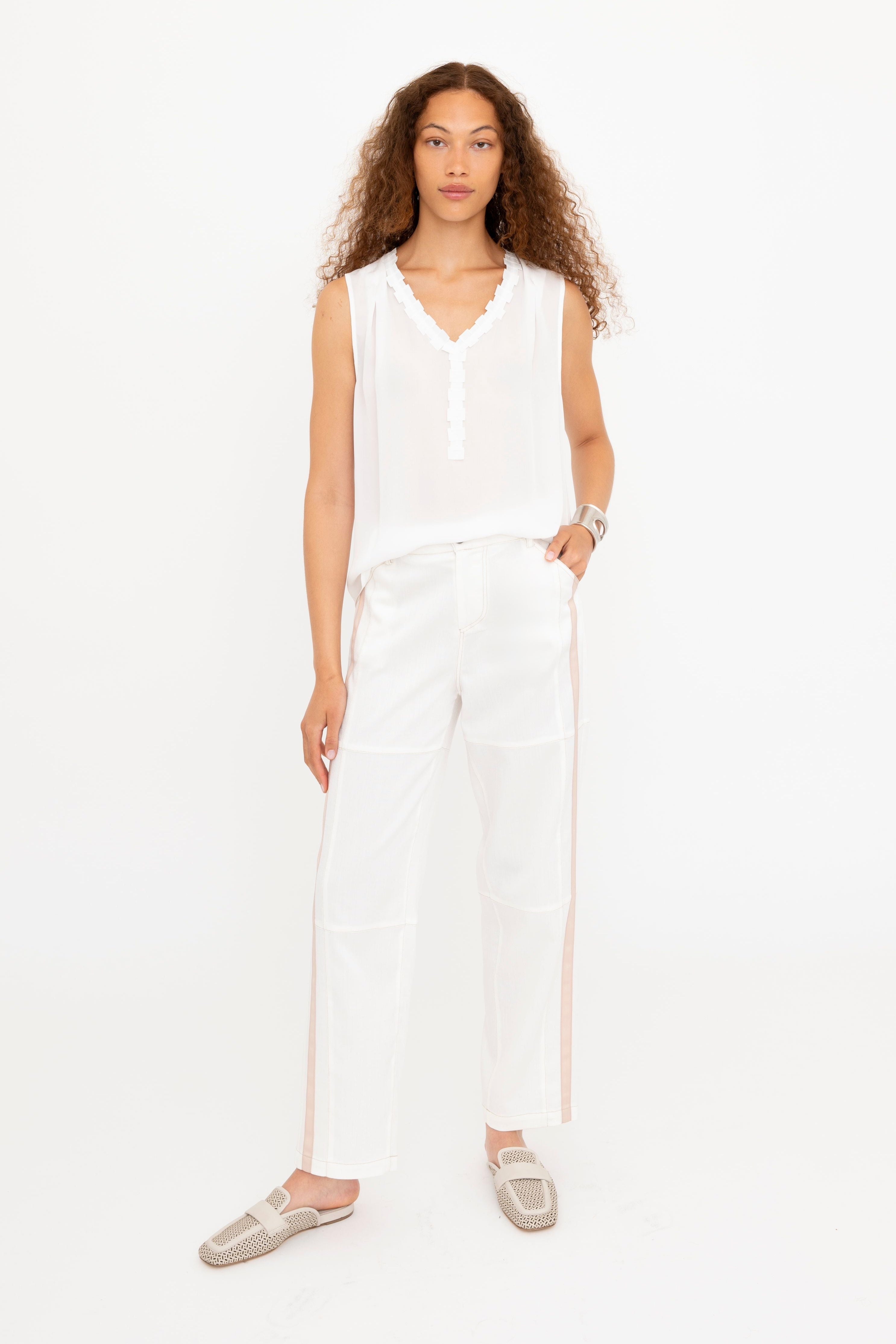 Woman wearing a white sleeveless top and pants on a white background