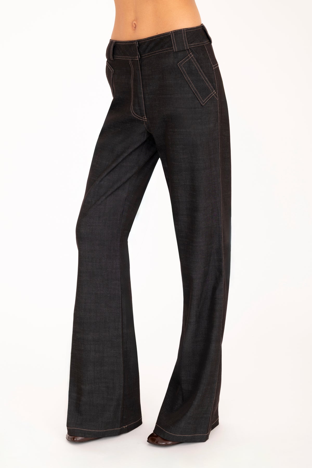 A woman wearing black wide-leg pants, shown from the waist down against a plain white studio background.