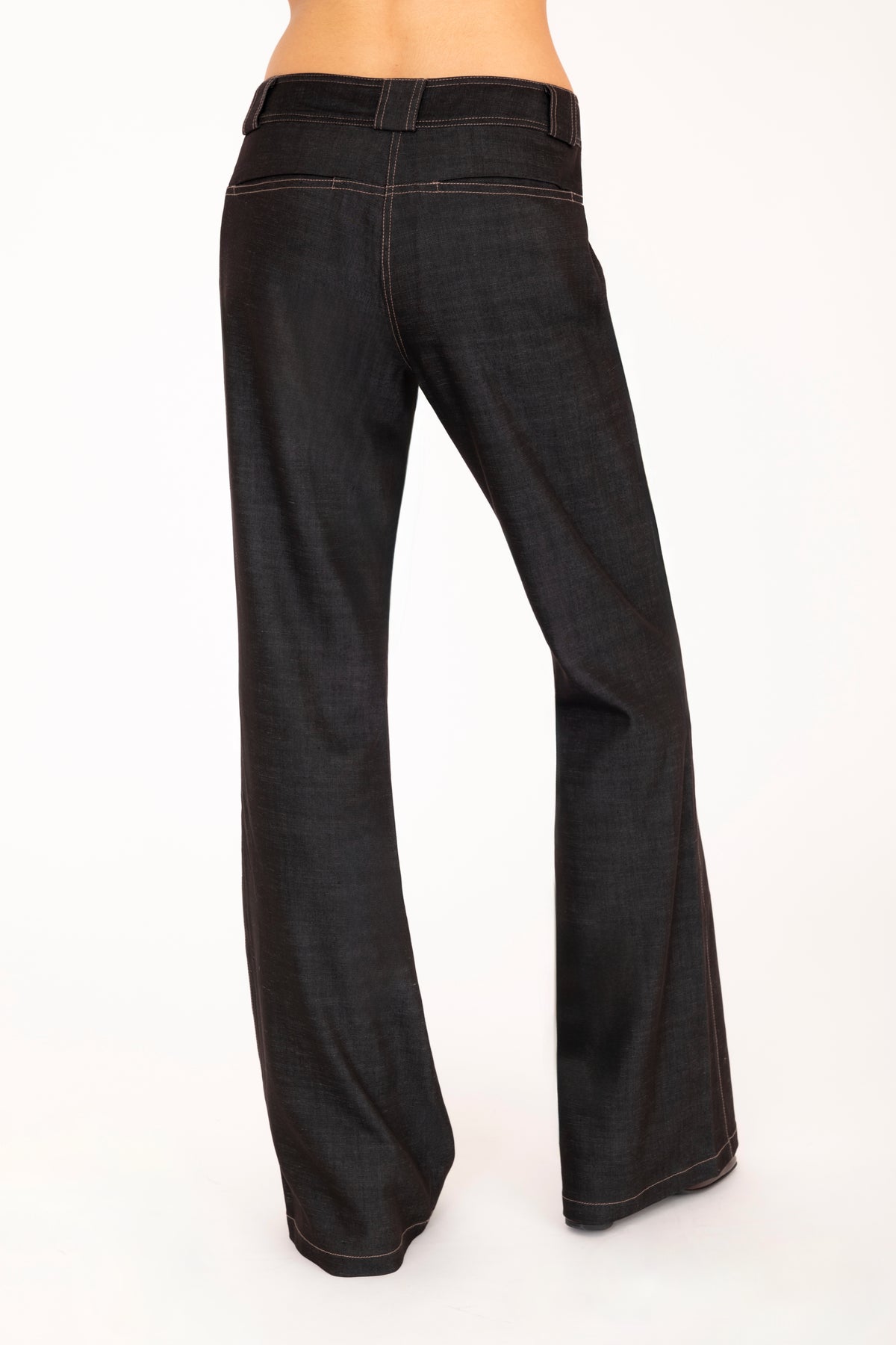 A woman wearing black wide-leg pants, shown from the waist down against a plain white studio background.