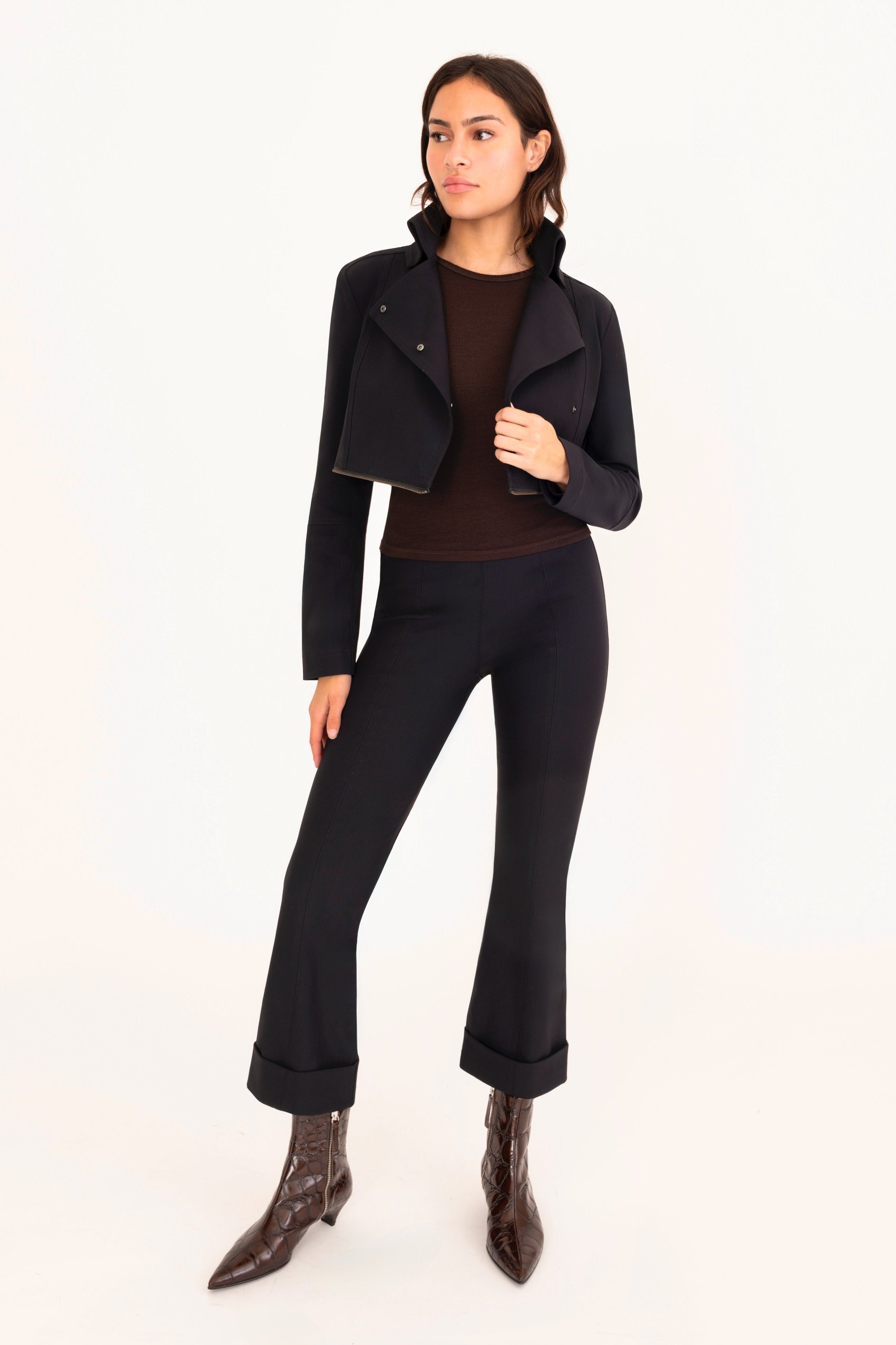 Woman wearing a black jacket and pants on a white background.