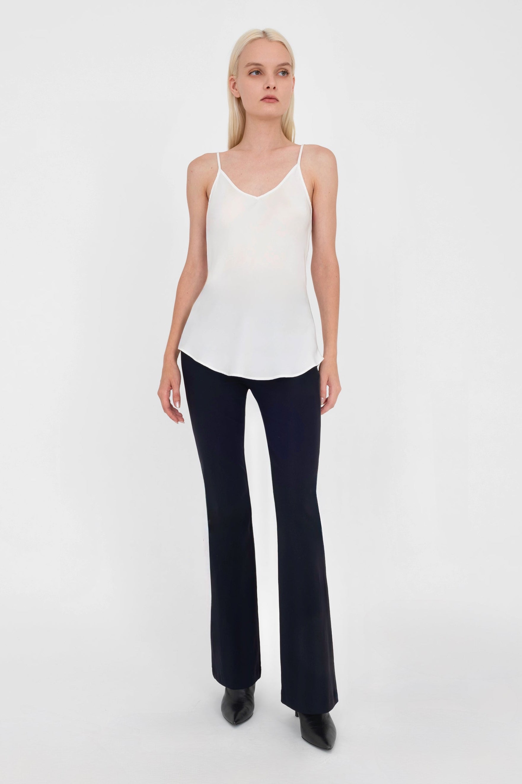Woman wearing white top and black pants on a white background