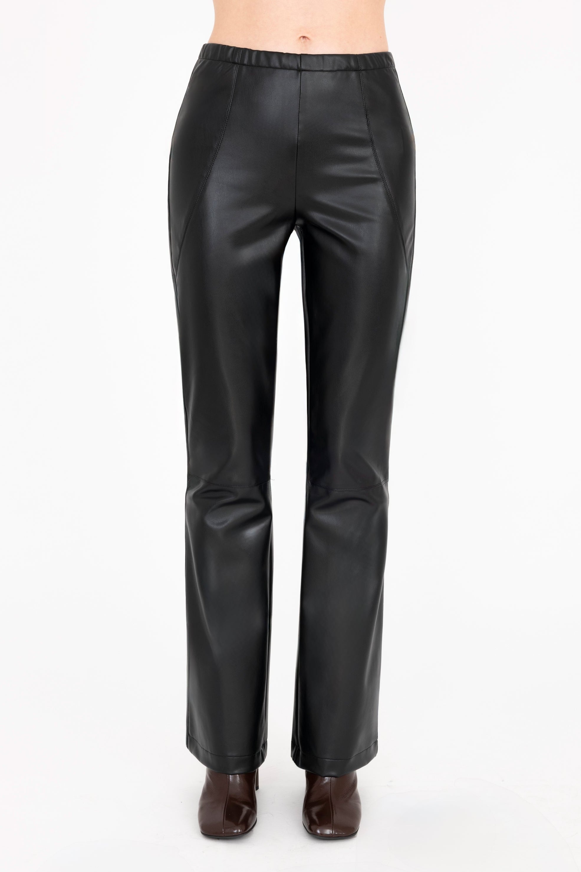 A model is shown from the waist down wearing high-waisted, wide-leg black  faux-leather pants and dark brown heeled boots against a plain off-white background.