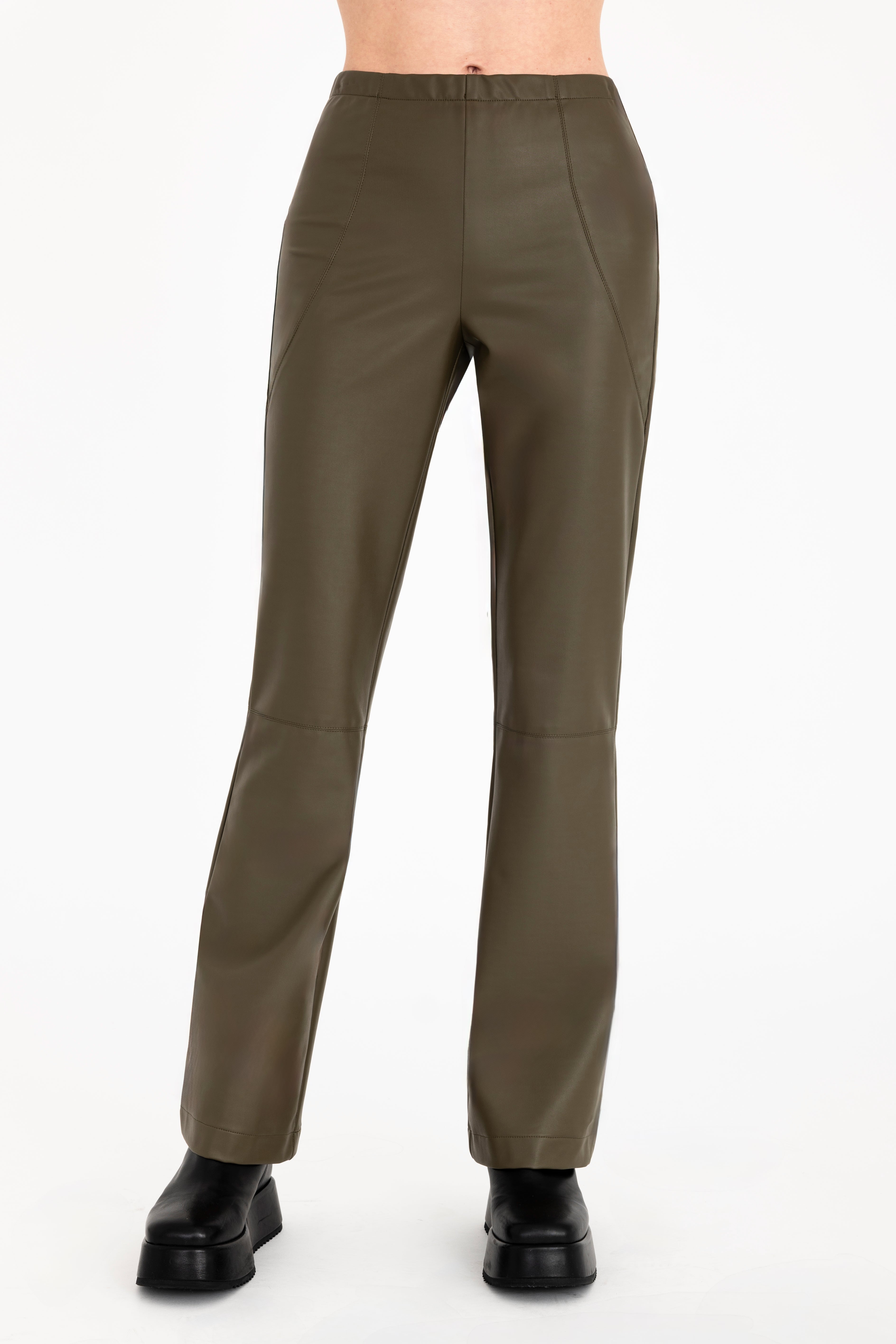 A model is shown from the waist down wearing high-waisted, wide-leg olive green faux-leather pants and dark brown heeled boots against a plain off-white background.