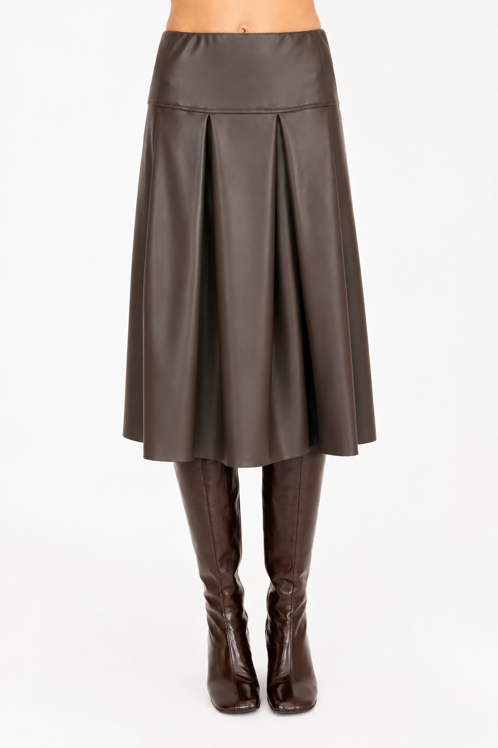 A brown vegan leather pleated A-line skirt shown on a model from the waist down, paired with dark brown knee-high leather boots against a plain white background.