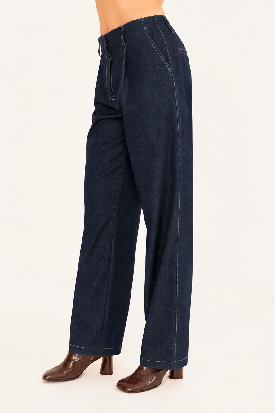 A model wearing dark cobalt blue wide-leg denim trousers with brown heeled boots, shown from the waist down against a plain light background.