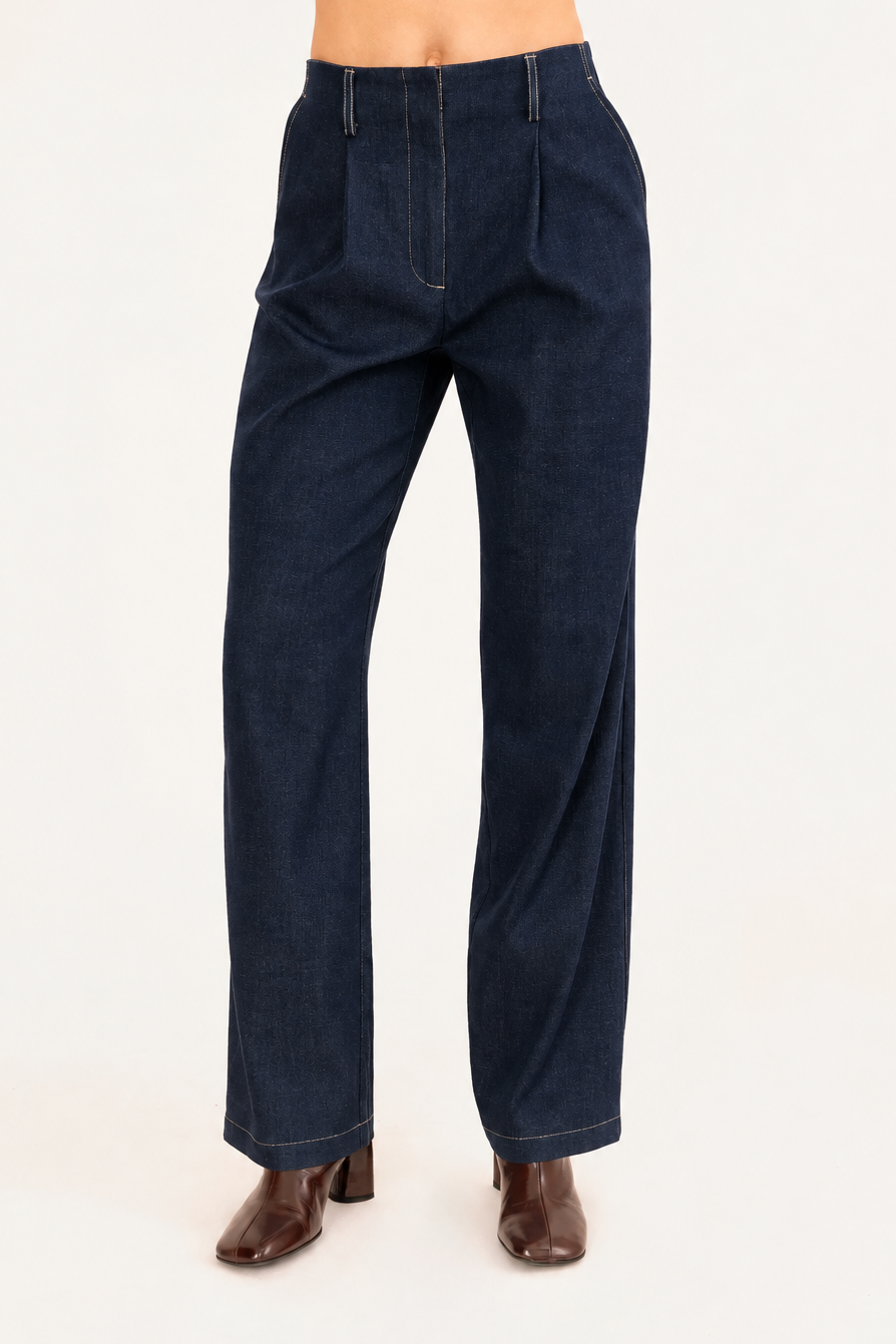 A model wearing dark cobalt blue wide-leg denim trousers with brown heeled boots, shown from the waist down against a plain light background.
