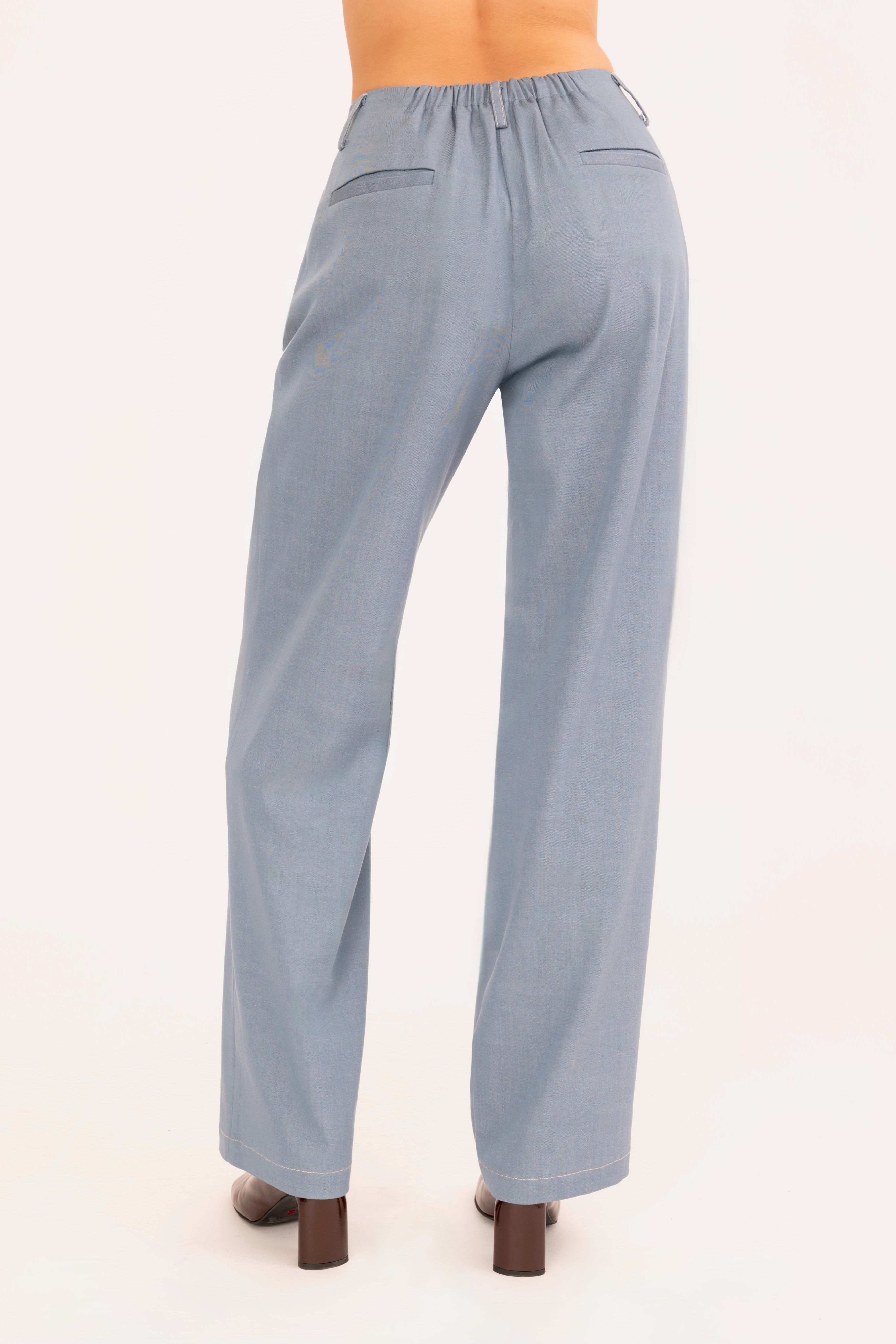 A model is shown from the waist down wearing a pair of light blue denim trousers and dark brown heeled boots against a plain off-white background.