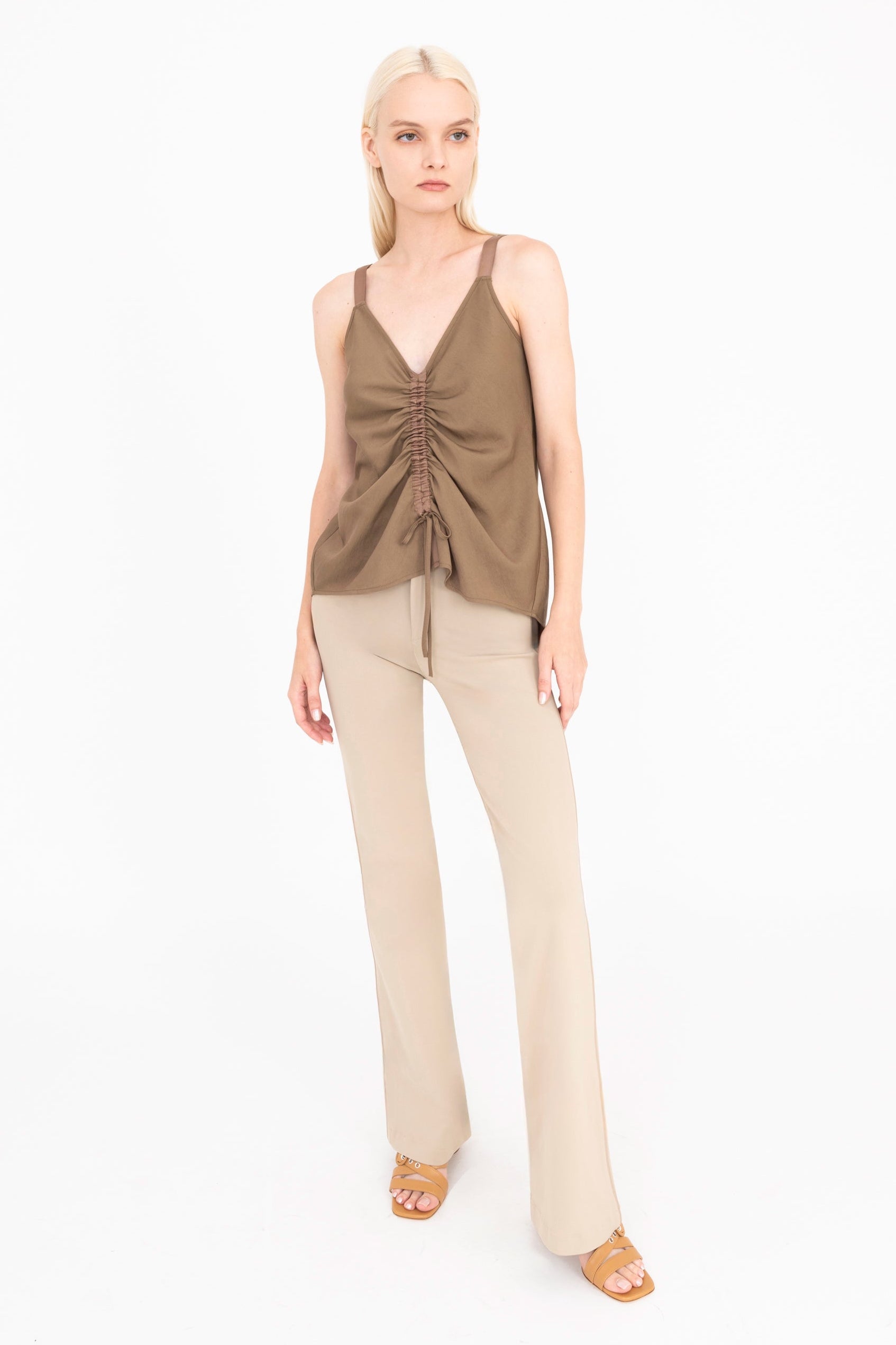 Woman wearing a brown top and beige pants on a white background