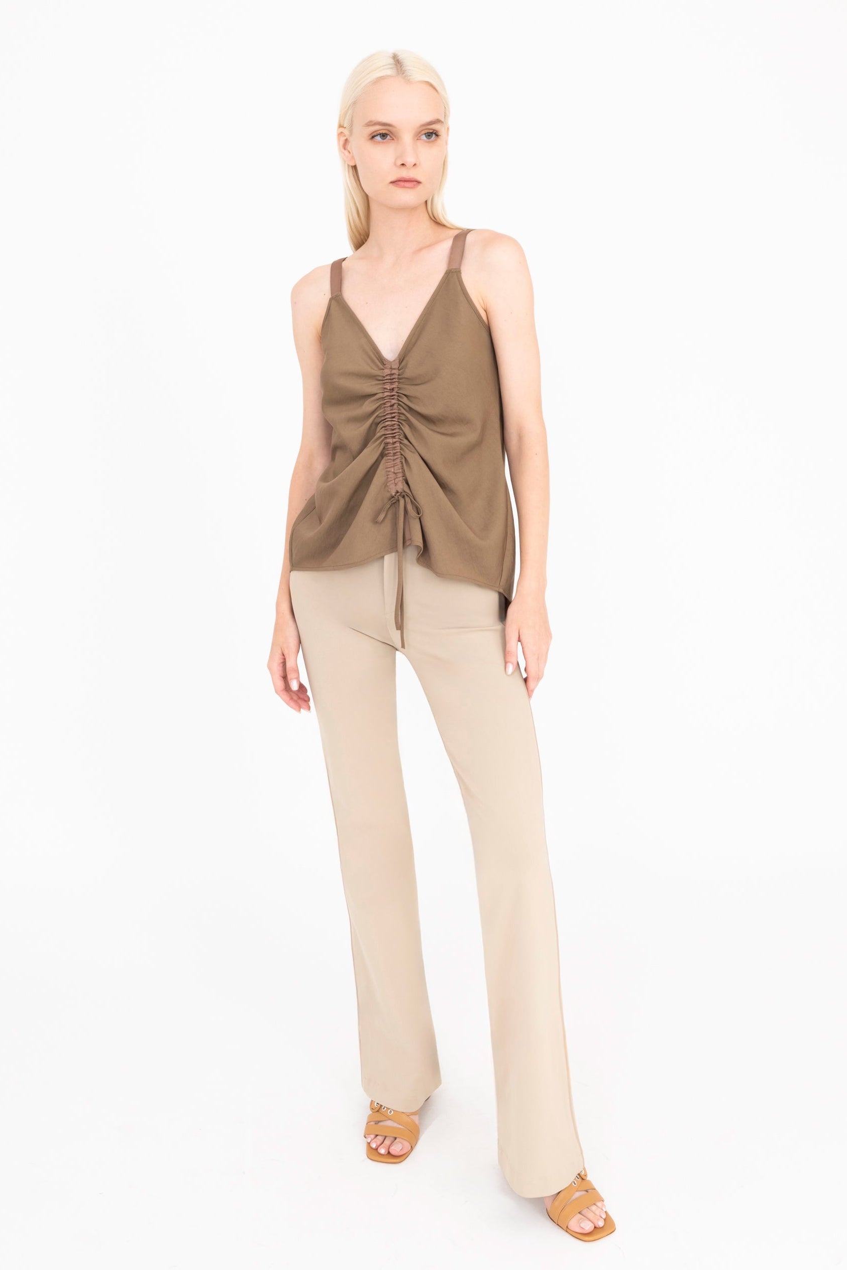 Woman wearing a brown top and beige pants on a white background