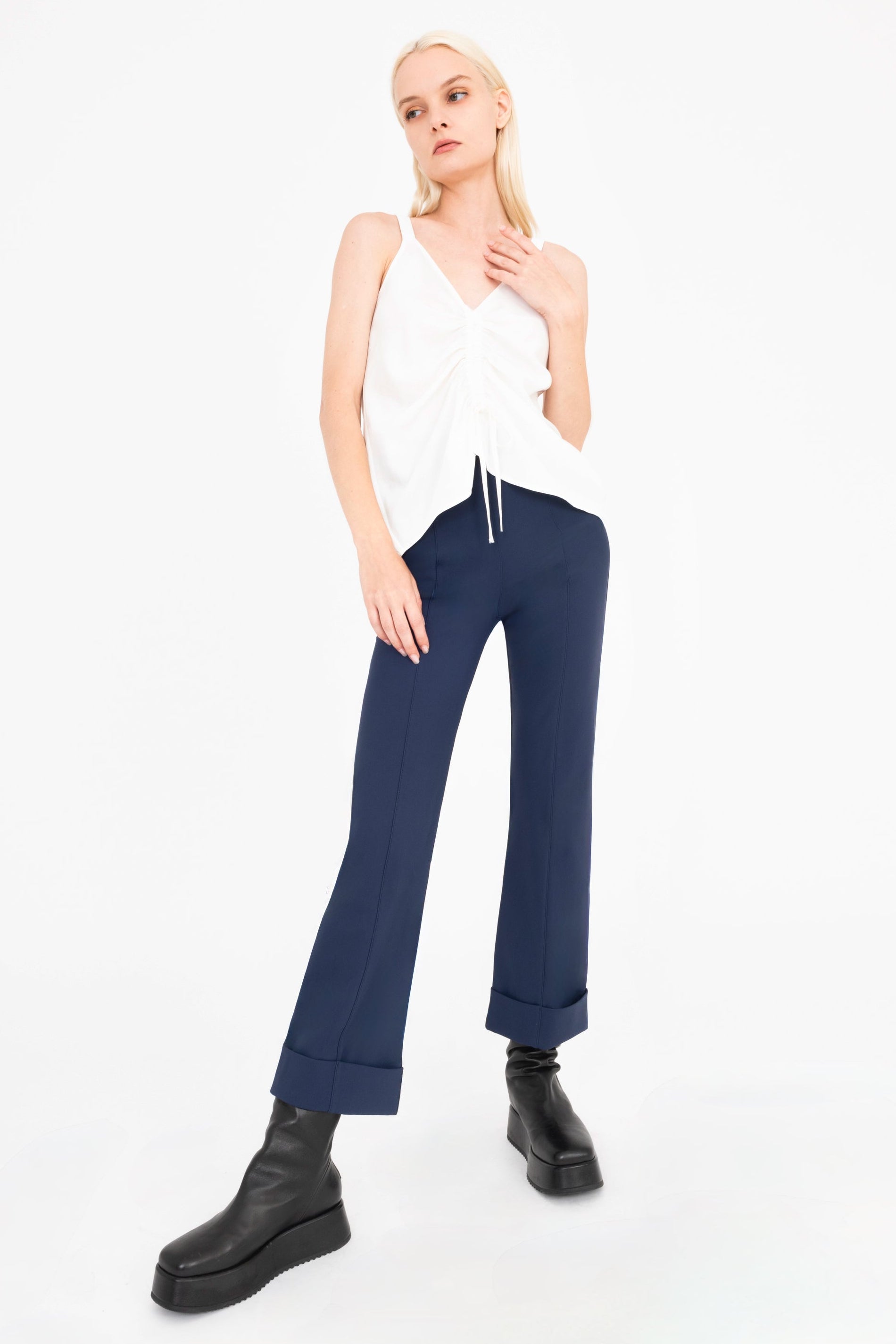 Woman wearing a white camisole and indigo pants on a white background