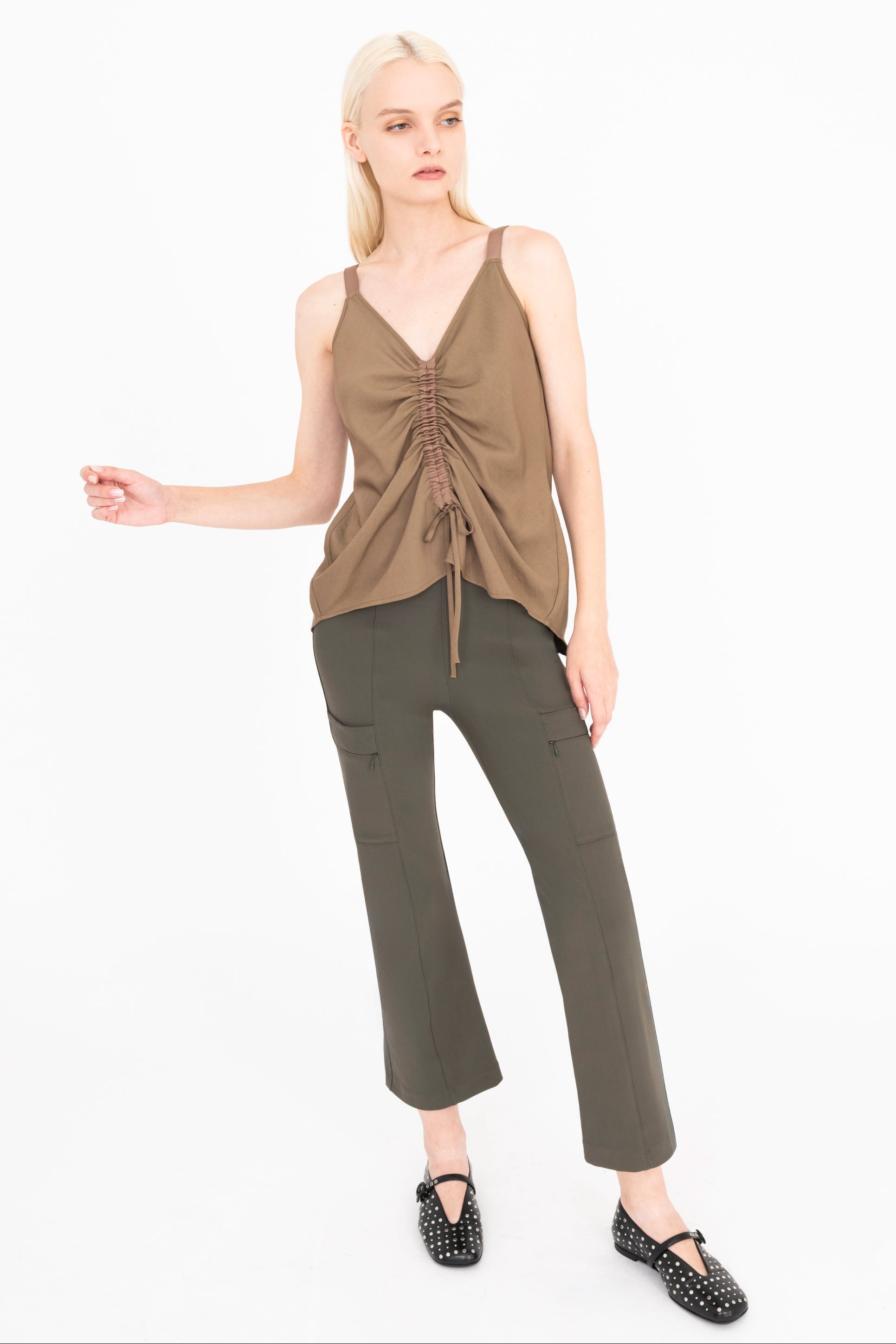 Woman wearing a brown top and green pants on a white background