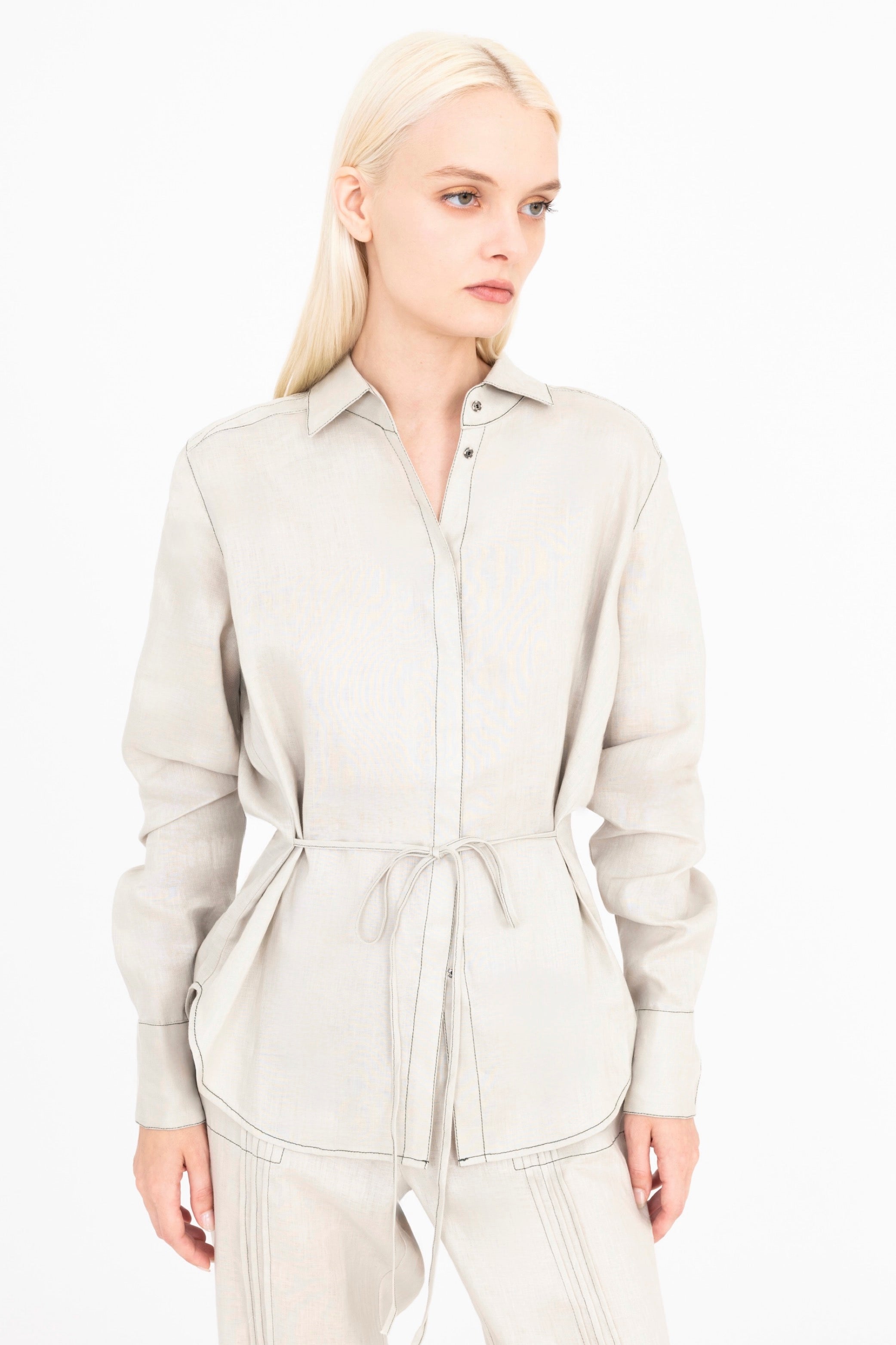 Woman wearing a beige shirt and pants on a white background
