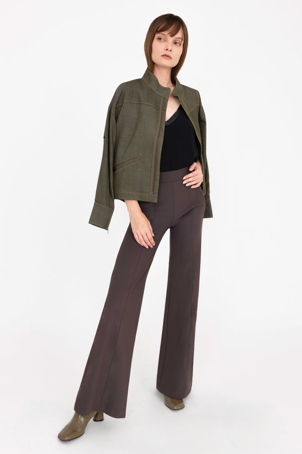Woman wearing a green jacket and brown pants on a white background