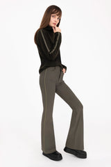 Woman wearing a black turtleneck and gray flared pants on a white background