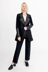 Person wearing a black suit with leather sleeves on a white background