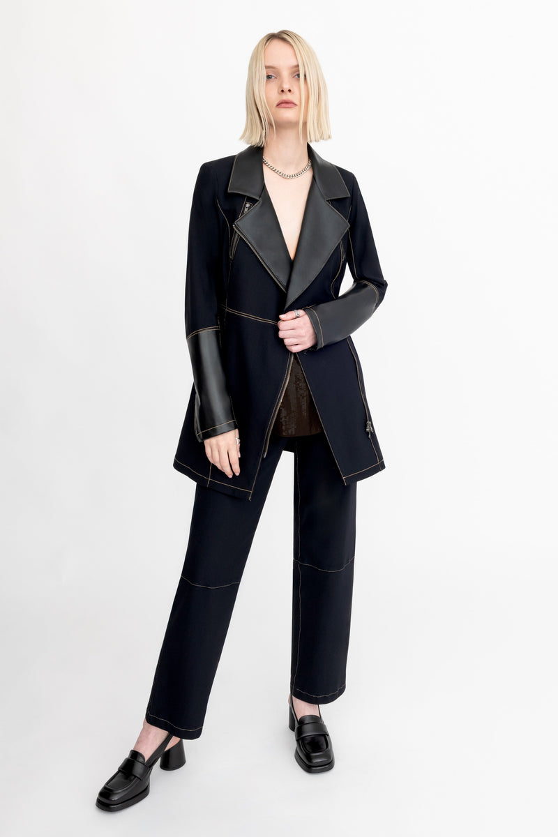 Person wearing a black suit with leather sleeves on a white background