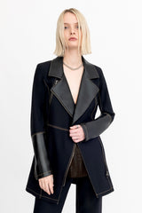 Person wearing a black suit with leather sleeves on a white background