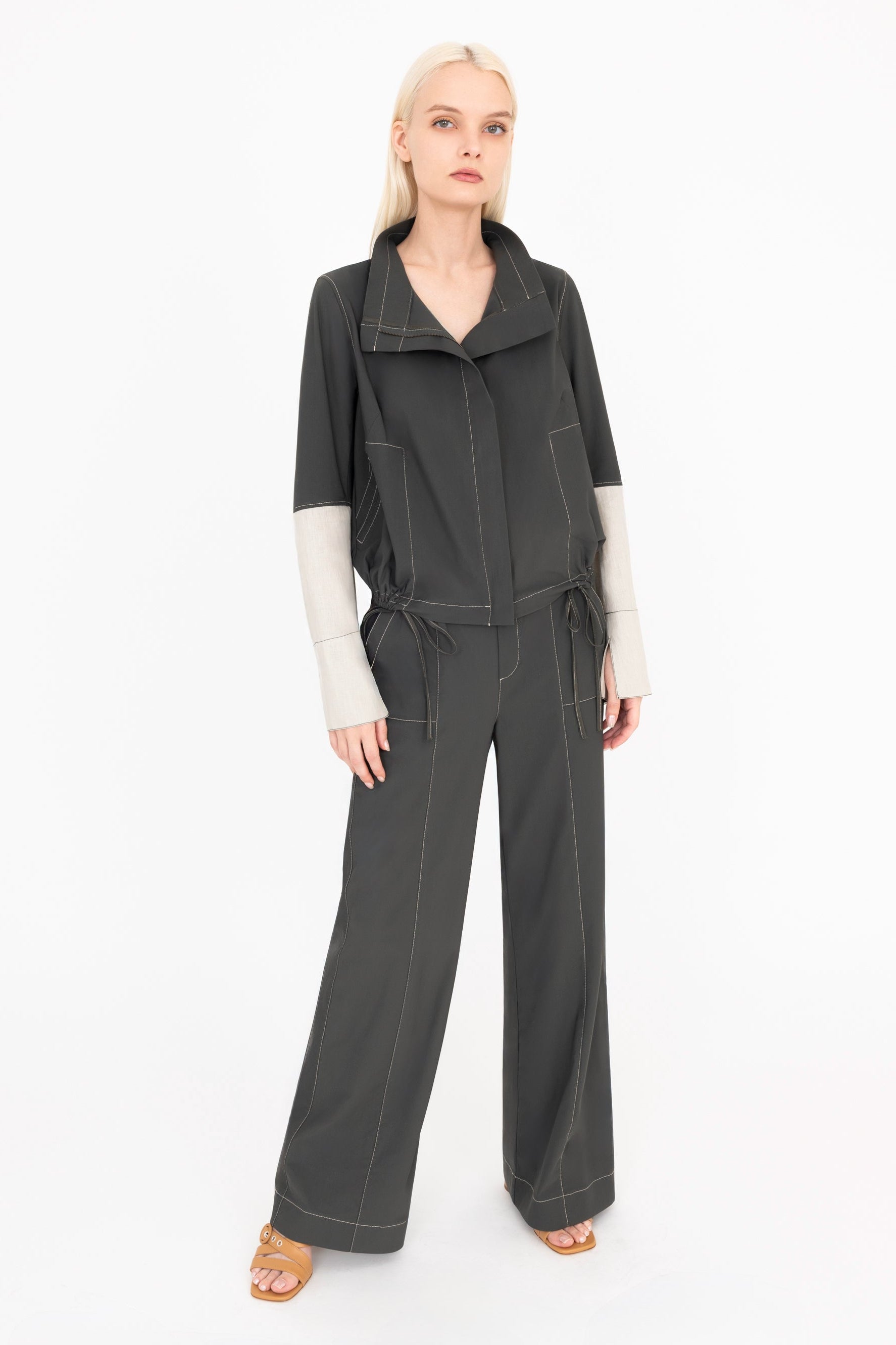 Woman wearing pine green jacket and pants on a white background