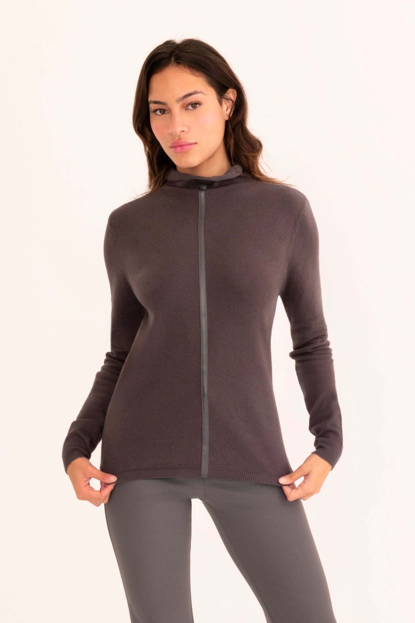 Front view of a woman wearing a gray funnel neck top and gray pants on a white background