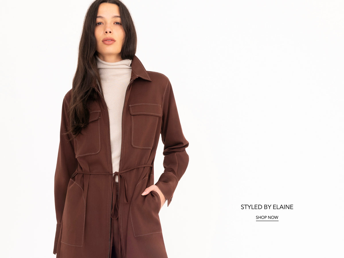 A woman modeling a brown mid-length denim coat over a cream turtleneck sweater, set against a plain white background with 'Styled by Elaine' text on the right.