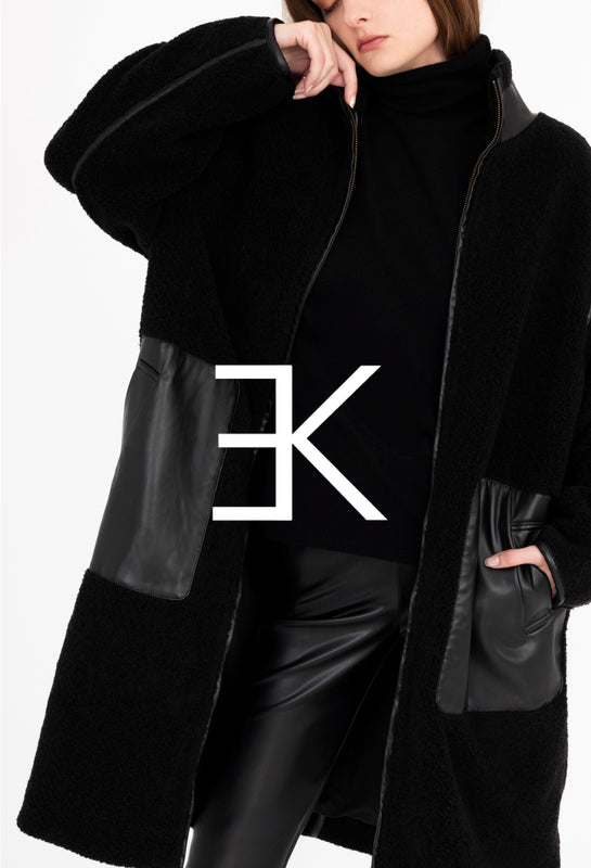 Person wearing a black coat with leather sleeves and a visible brand logo on a white background