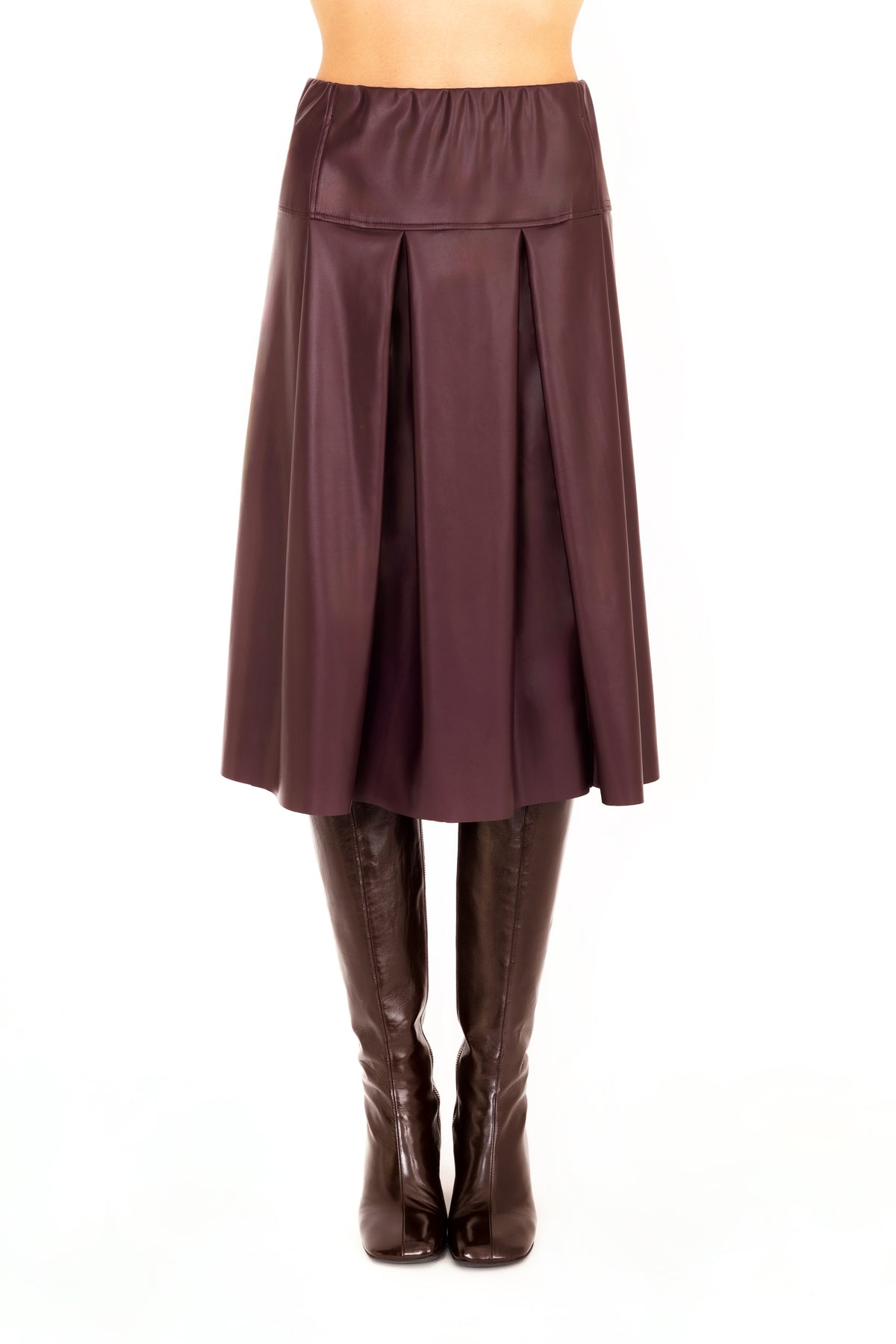 A burgundy vegan leather pleated A-line skirt shown on a model from the waist down, paired with dark brown knee-high leather boots against a plain white background.