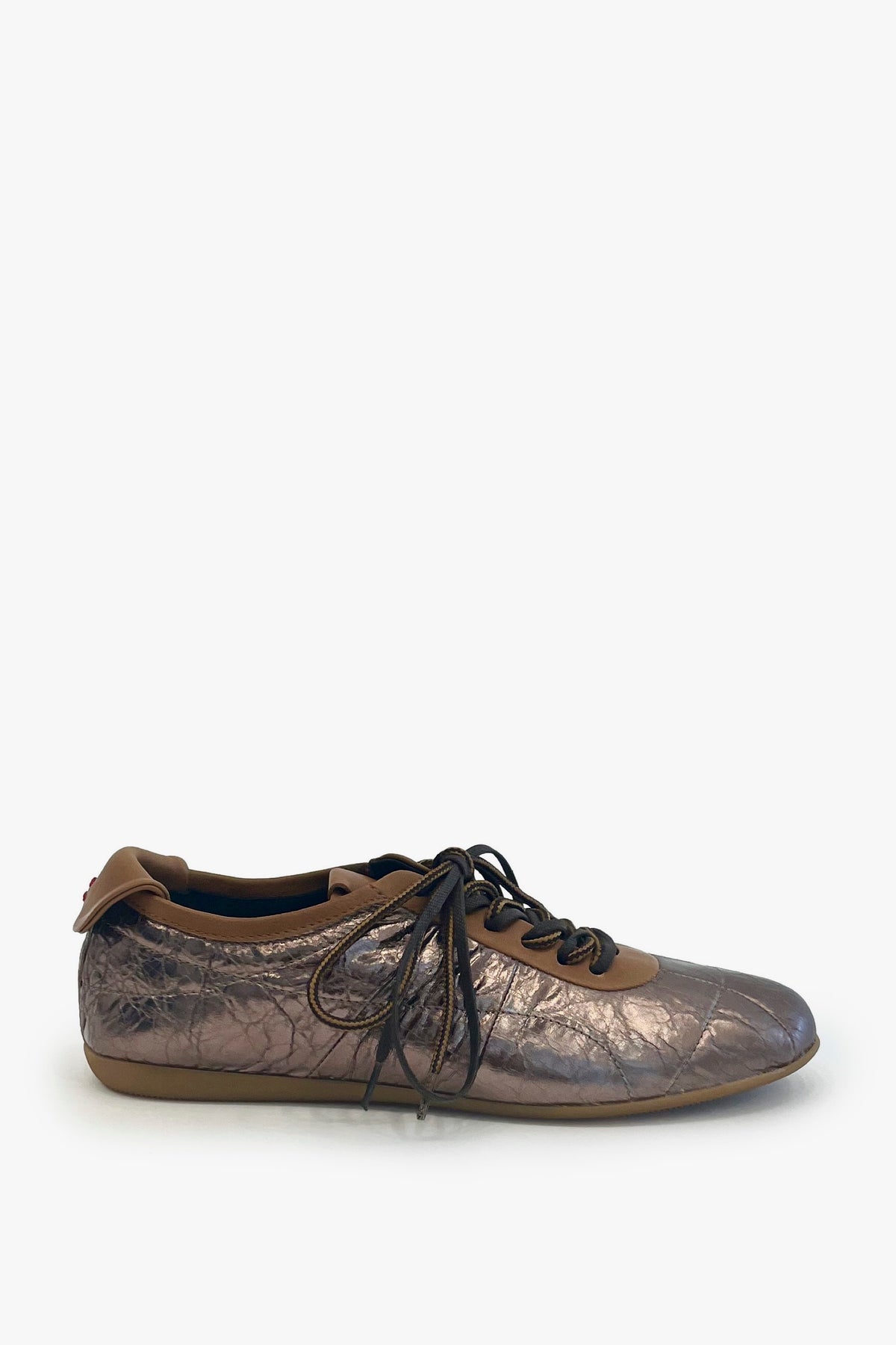 A single metallic bronze sneaker with brown laces, shown from a side angle on a light gray background.