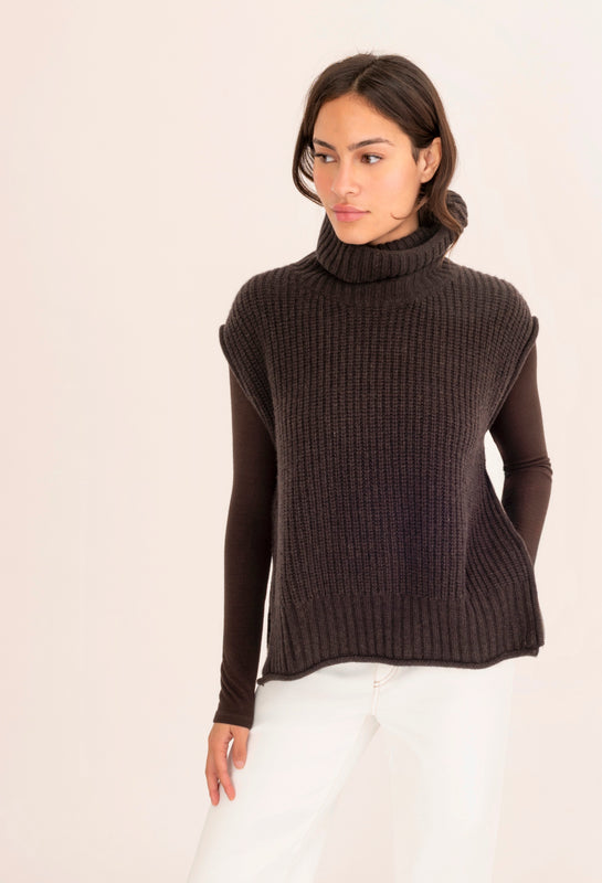 Woman wearing a dark brown ribbed turtleneck sweater on a white background