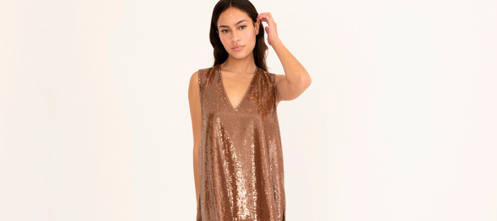 Woman wearing a bronze sequin sleeveless top on a white background