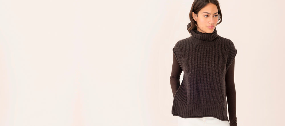 Woman wearing a dark brown turtleneck sweater on a light beige background