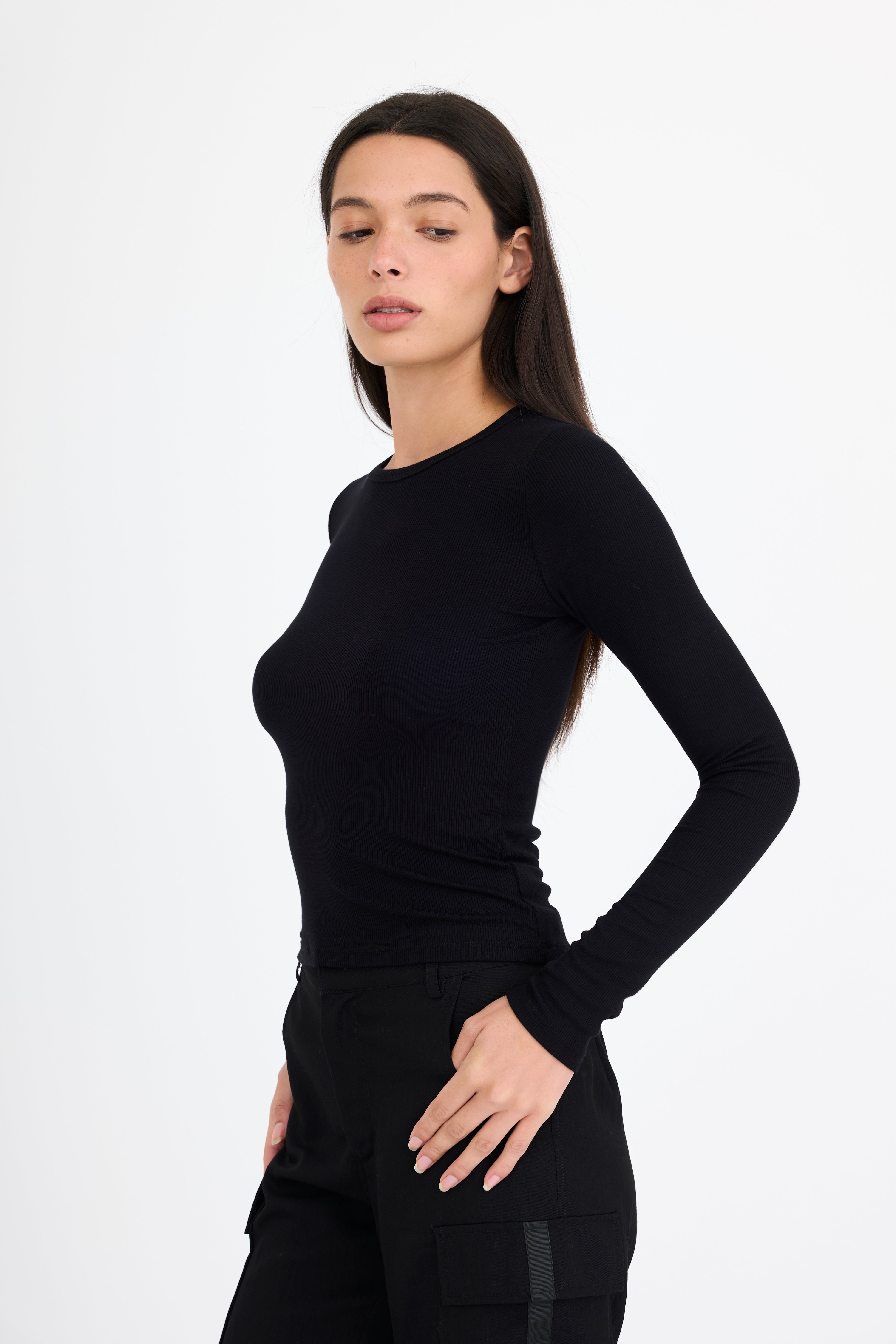 Woman wearing a black long-sleeve t-shirt and black pants on a white background