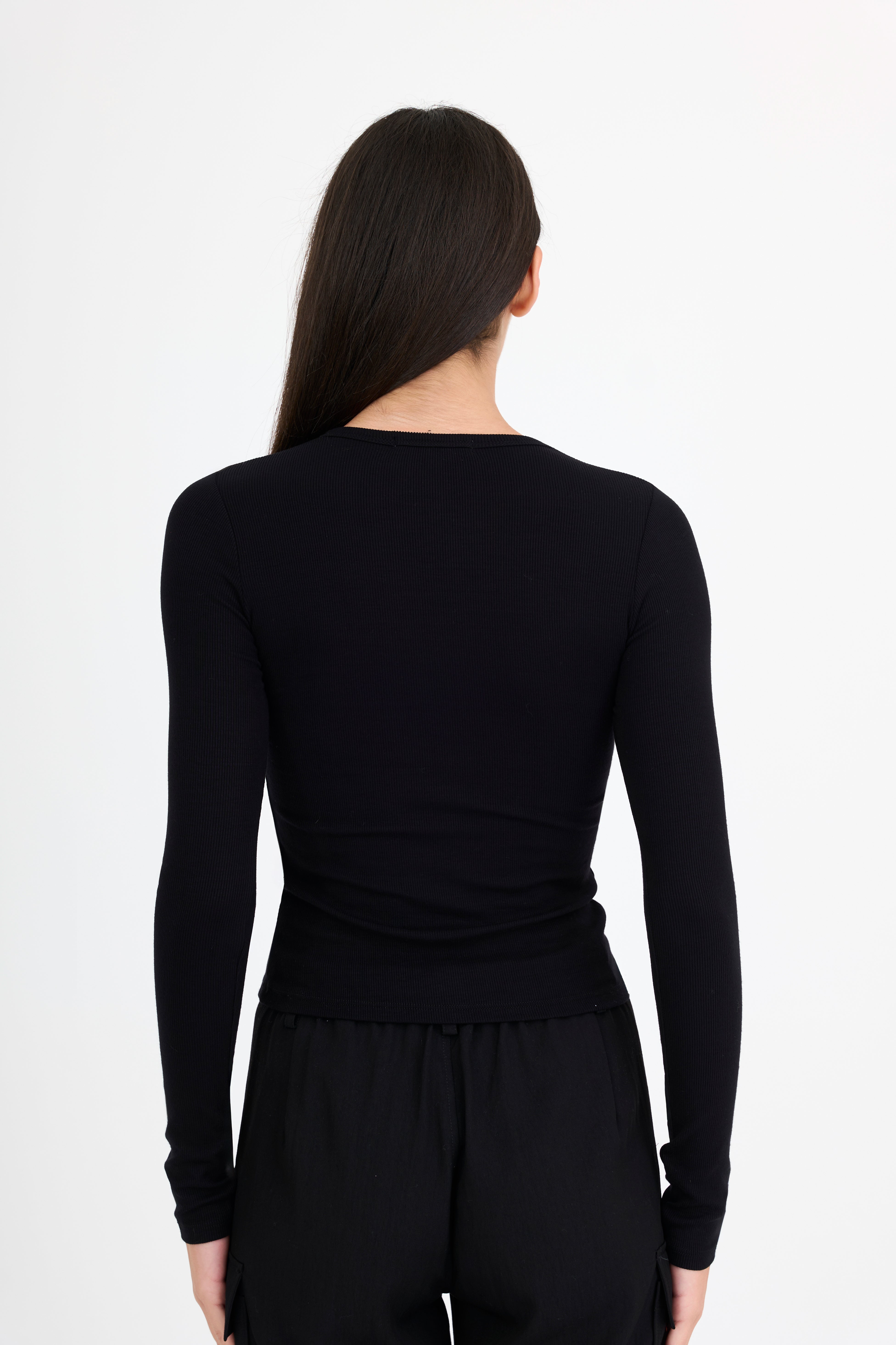 Woman wearing a black long-sleeve t-shirt and black pants on a white background