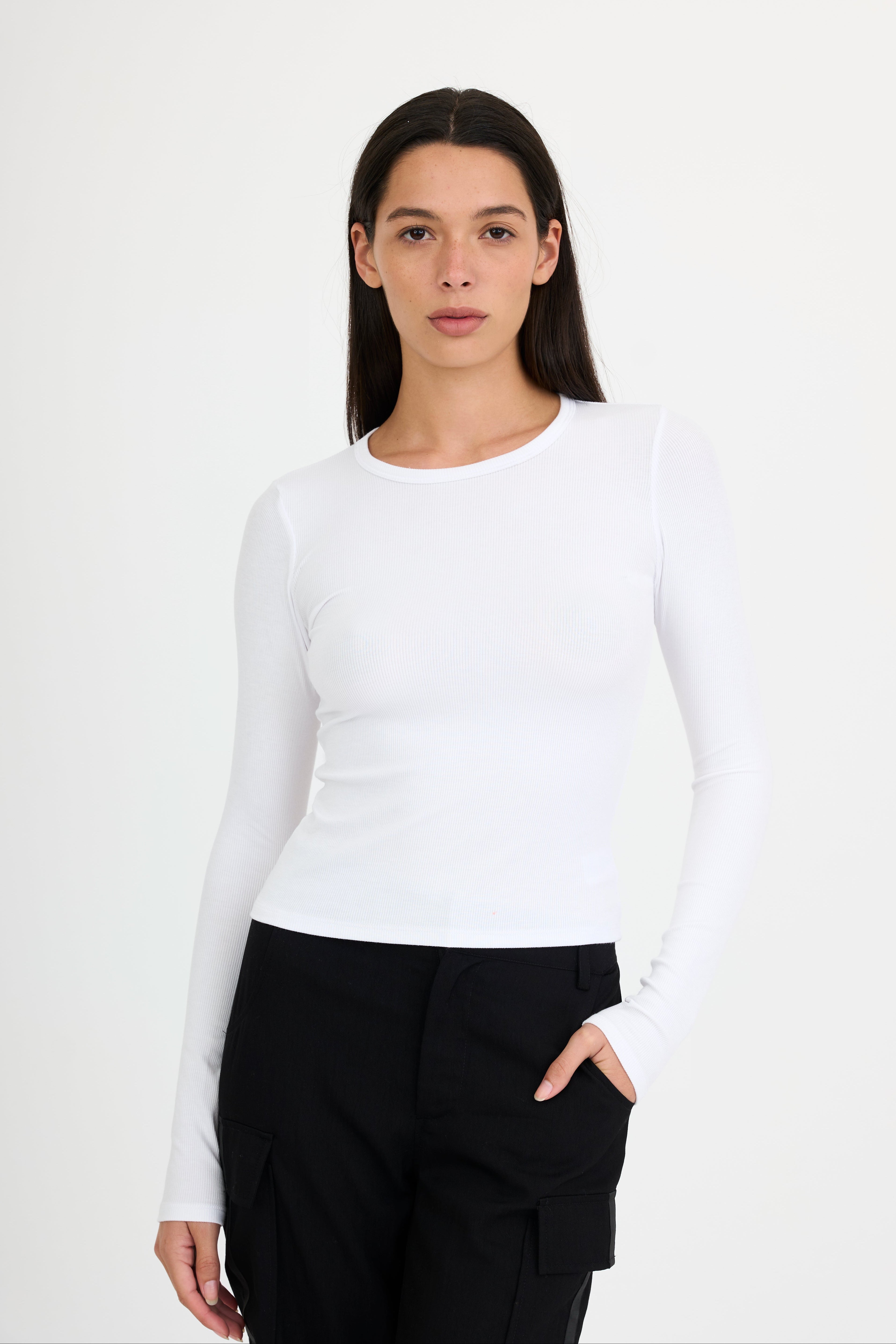 Woman wearing a white long-sleeve t-shirt and black pants on a white background