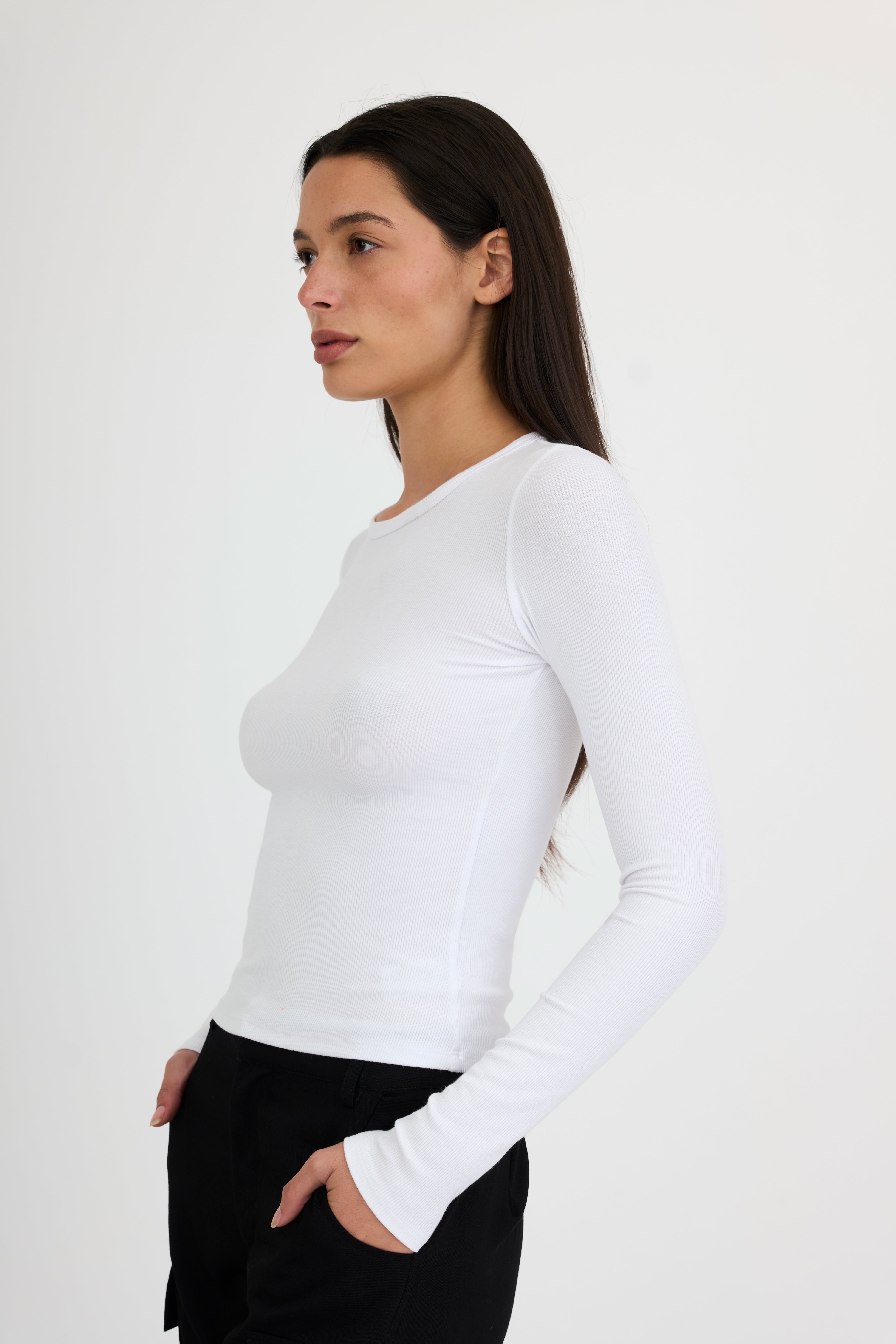 Woman wearing a white long-sleeve t-shirt and black pants on a white background