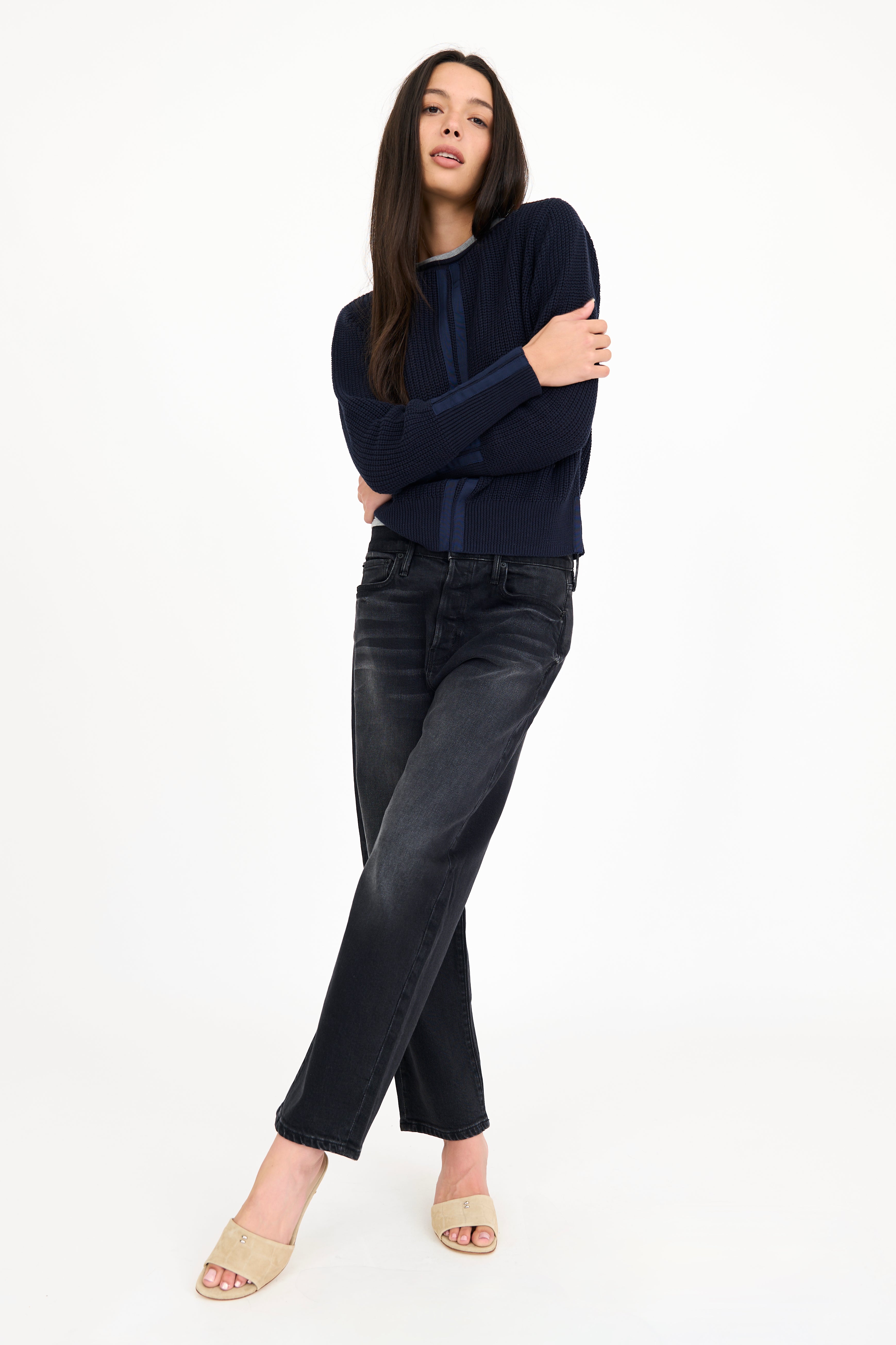Woman wearing a navy sweater and black jeans on a white background