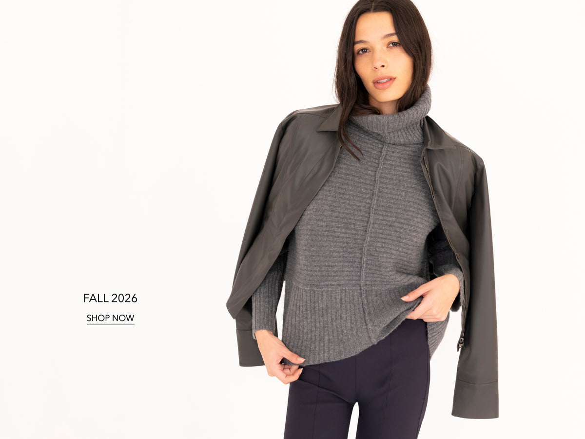 A model wearing a dark gray ribbed turtleneck sweater under an open dark gray jacket, paired with dark blue pants, on a clean white background with 'FALL 2026 SHOP NOW' text on the left.