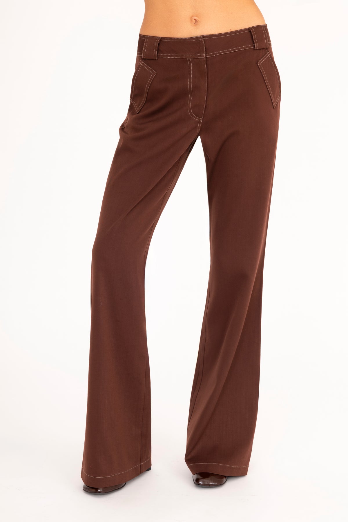 A woman wearing brown wide-leg pants, shown from the waist down against a plain white studio background.
