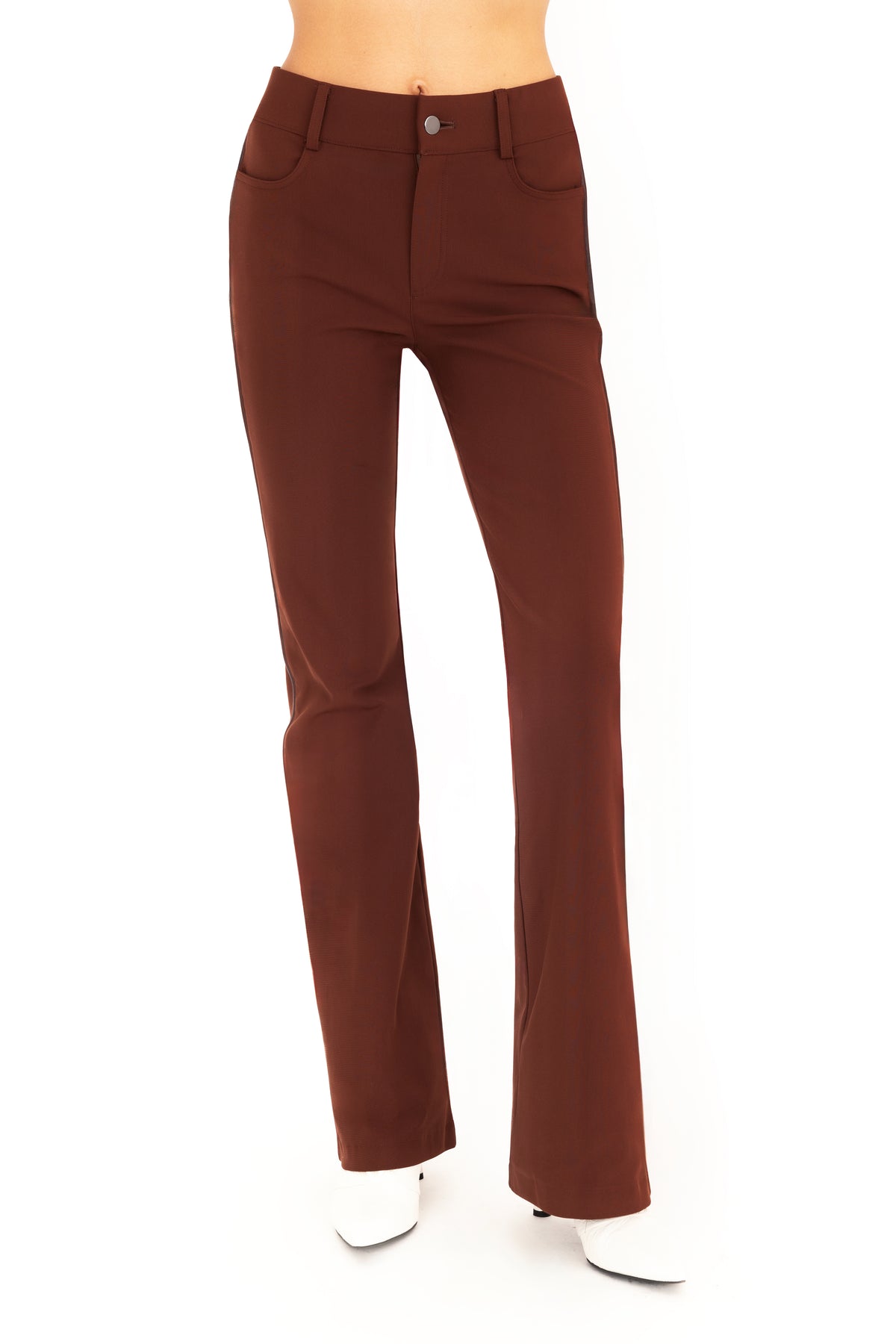 A pair of dark brown flare jean pants shown on a model from the waist down, paired with white pointed-toe boots against a plain white background.