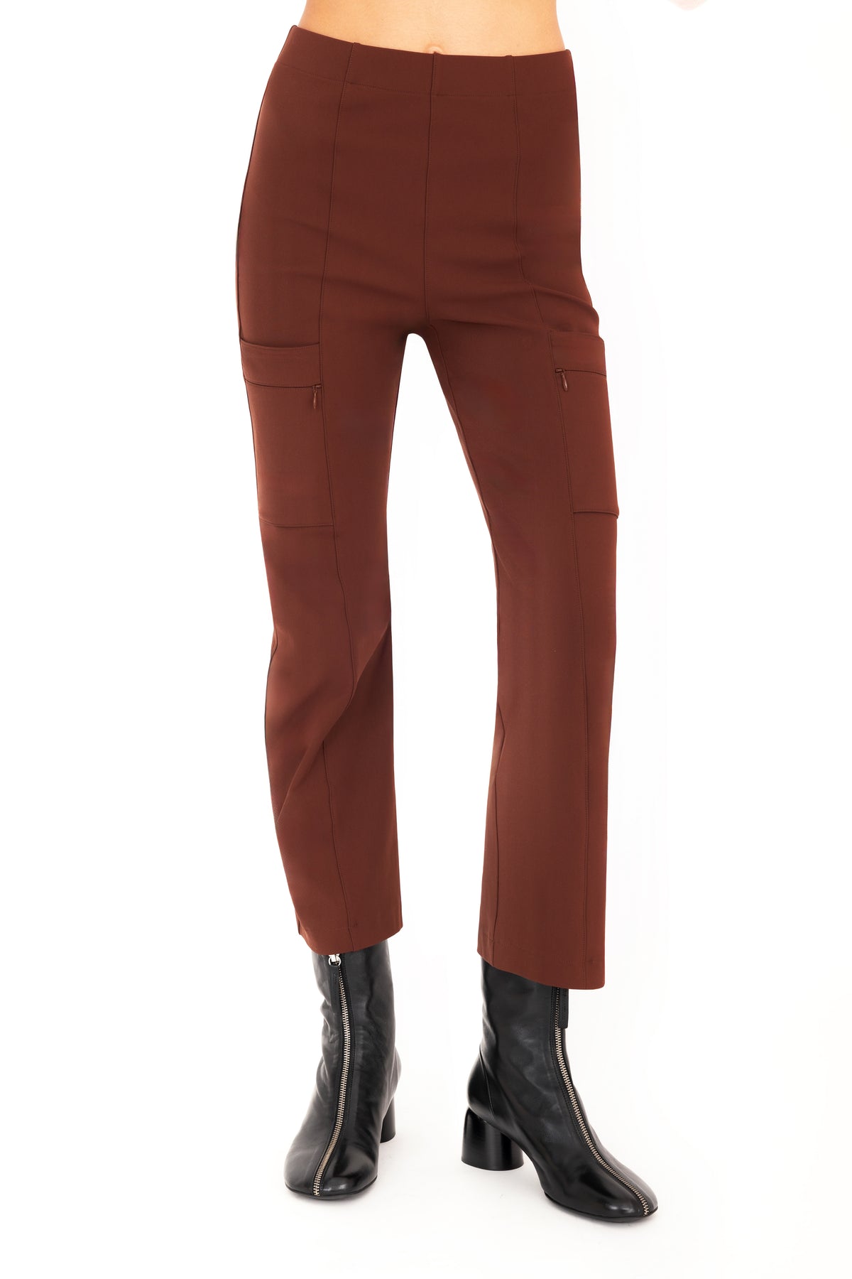 A model wearing brown cropped pants with side zip pockets and black ankle boots, shown from the waist down on a plain white studio background.