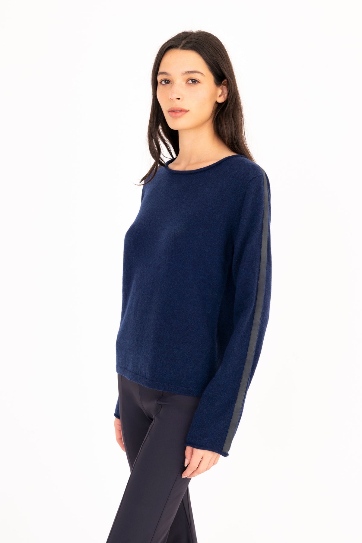 A woman modeling a navy blue long-sleeve knit sweater, paired with navy blue pants, against a plain white studio background.
