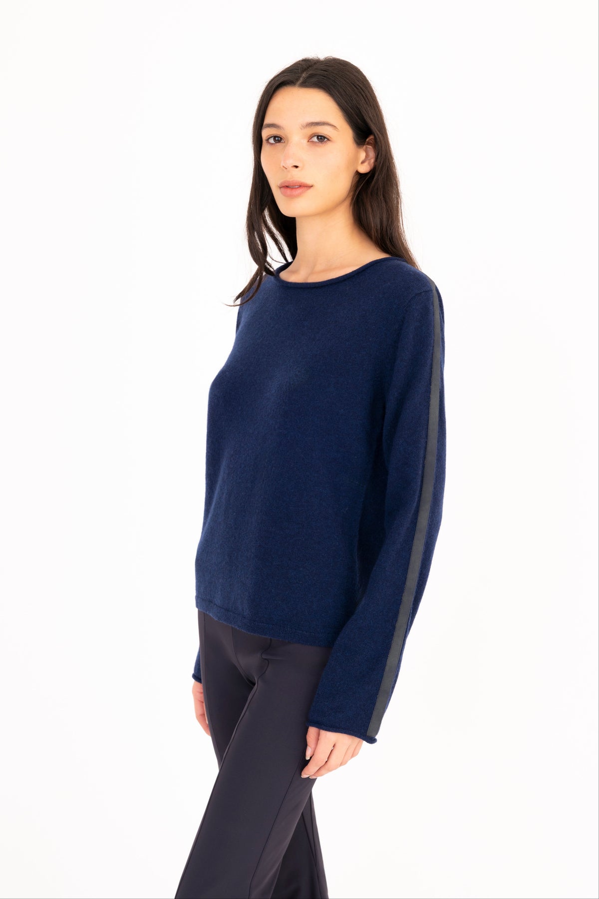 A woman modeling a navy blue long-sleeve knit sweater, paired with navy blue pants, against a plain white studio background.