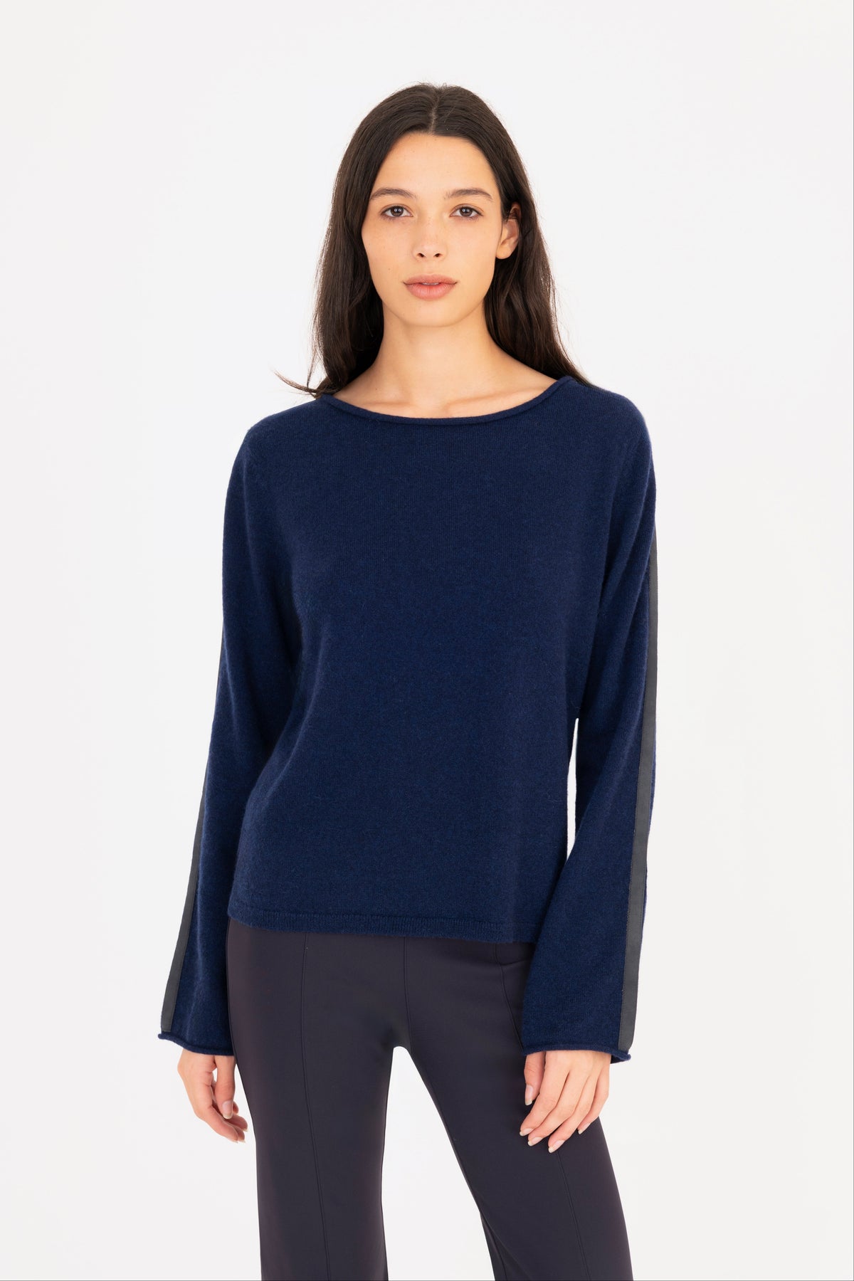 A woman modeling a navy blue long-sleeve knit sweater, paired with navy blue pants, against a plain white studio background.