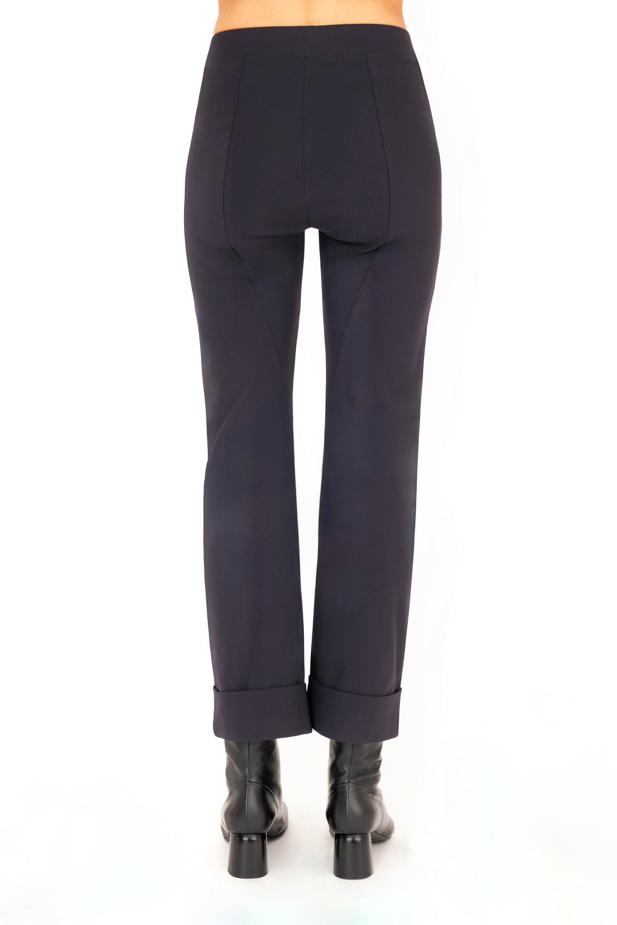 A model shown from the back wearing dark navy cropped pants with rolled cuffs and black ankle boots, shown from the waist down on a white studio background.