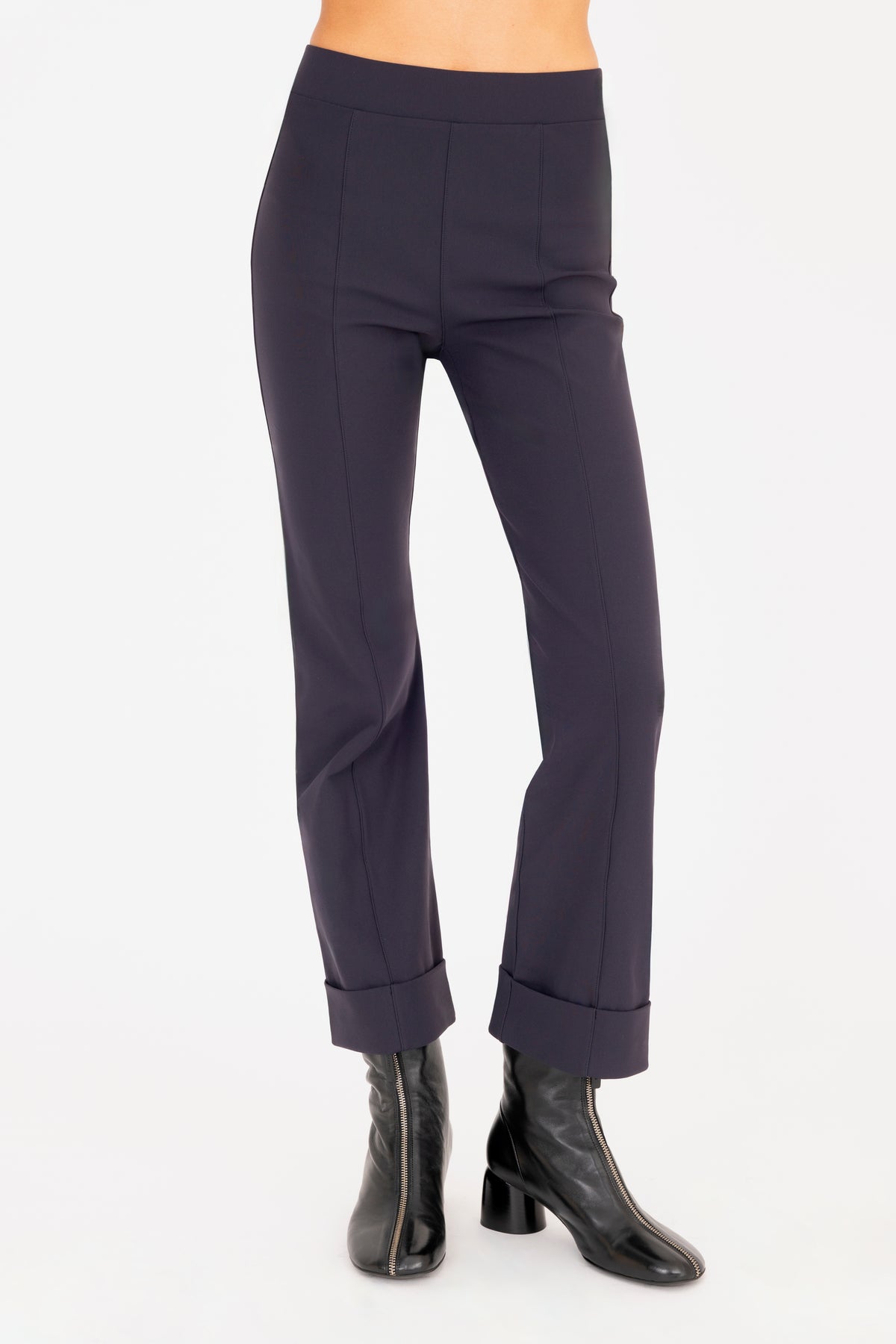 A model wearing dark navy cropped pants with rolled cuffs and black ankle boots, shown from the waist down on a white studio background.