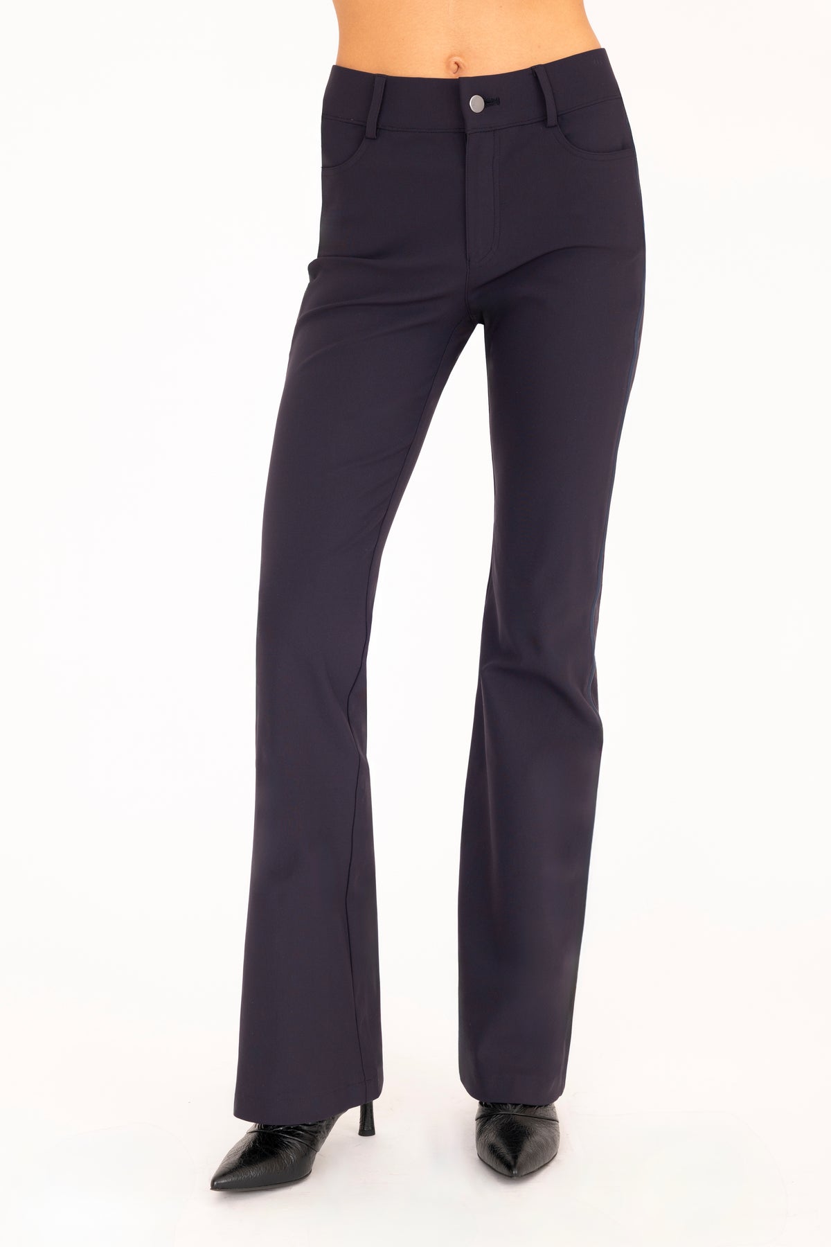 A pair of dark blue flare jean pants shown on a model from the waist down, paired with black pointed-toe boots against a plain white background.