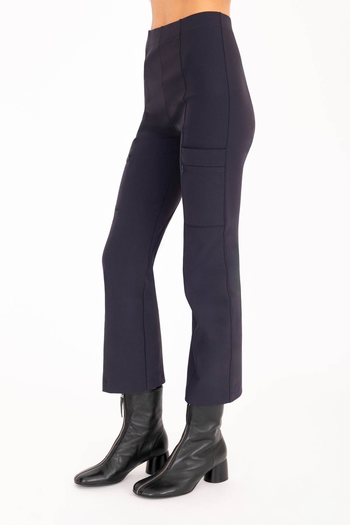 A model wearing dark navy cropped pants with side zip pockets and black ankle boots, shown from the waist down on a plain white studio background.