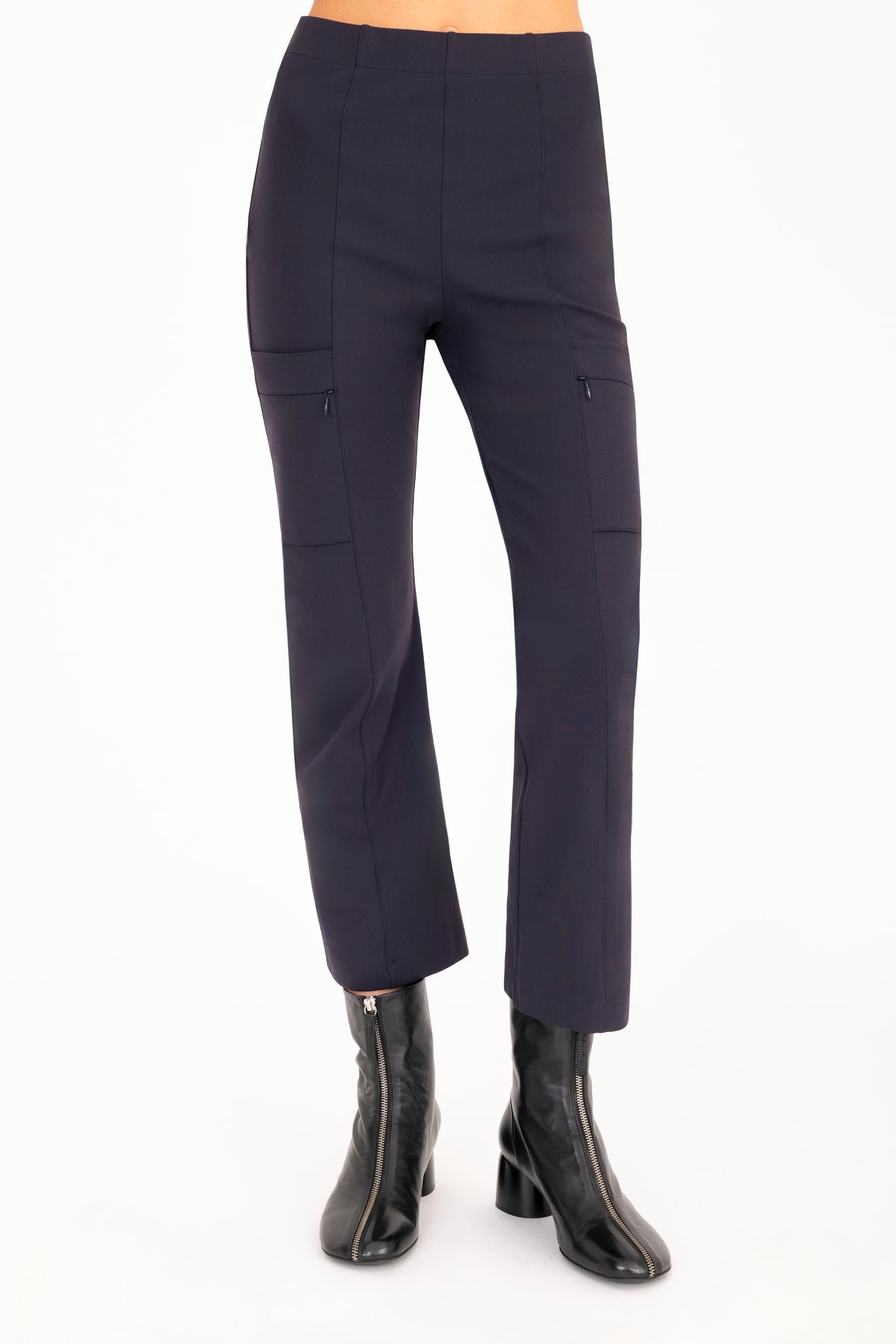 A model wearing dark navy cropped pants with side zip pockets and black ankle boots, shown from the waist down on a plain white studio background.