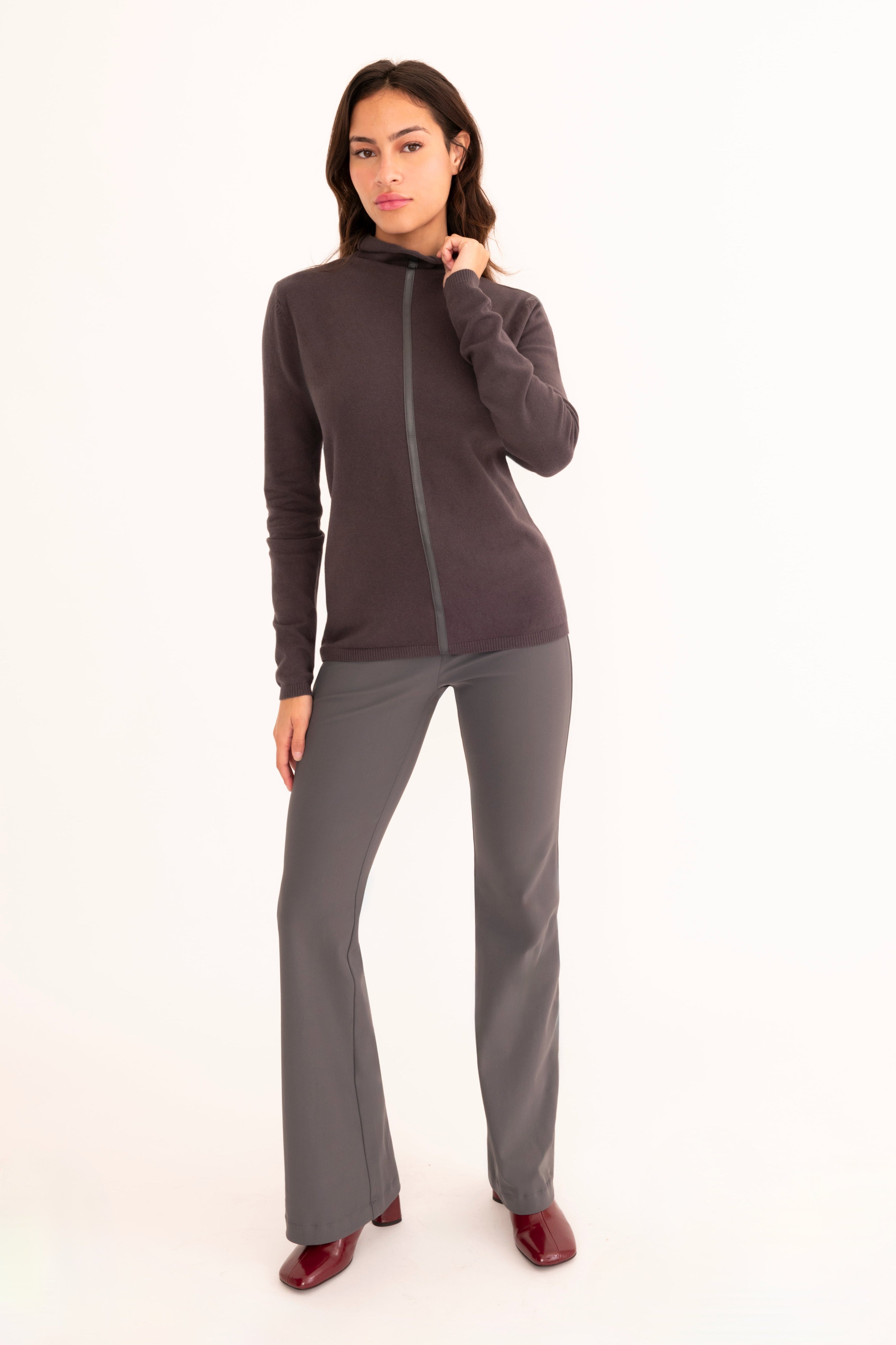 A woman modeling a dark gray long-sleeve zip-up sweater and matching gray pants against a plain white studio background.
